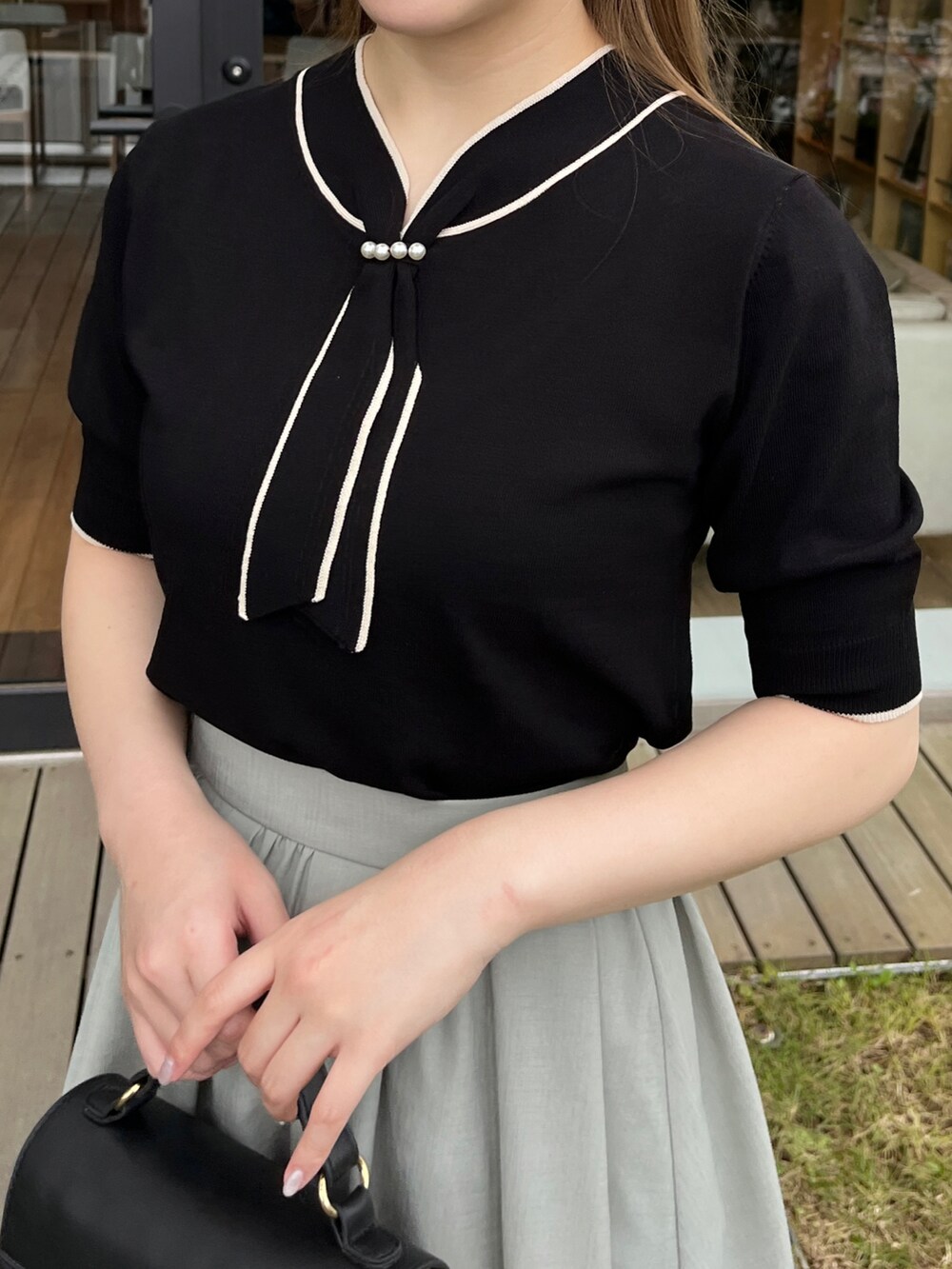 ブラック系のショルダーバッグ、ホワイト系のサンダル、グリーン系のスカートを着用したレディースの夏コーディネートの4枚目の写真