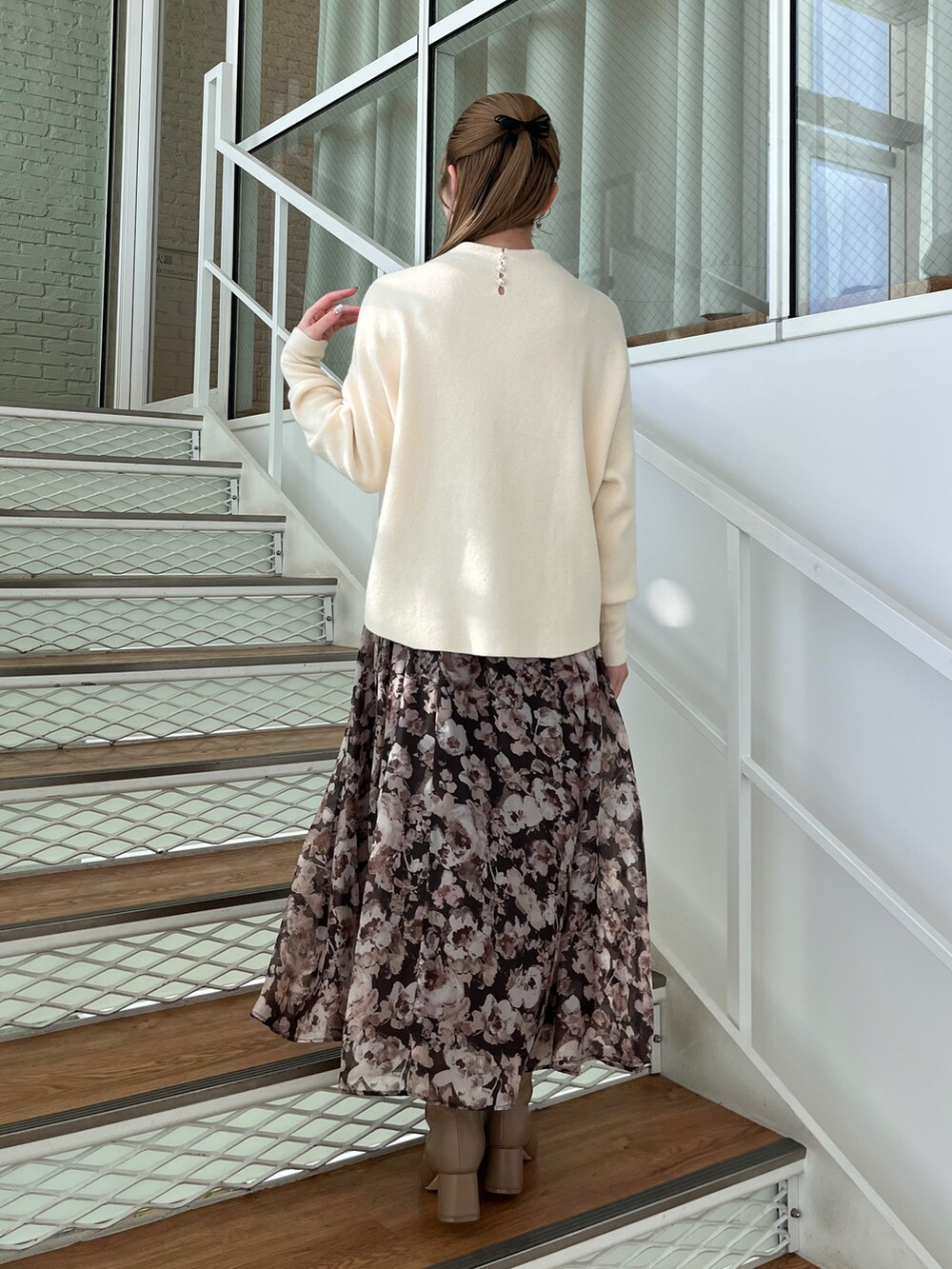 ホワイト系のニット/セーター、ブラウン系のスカート、ブラウン系のブーツを着用したレディースの秋コーディネートの2枚目の写真