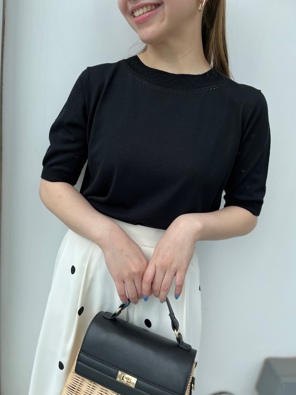 ブラック系のニット/セーター、ベージュ系のスカート、ブラック系のショルダーバッグを着用したレディースの春コーディネートの4枚目の写真
