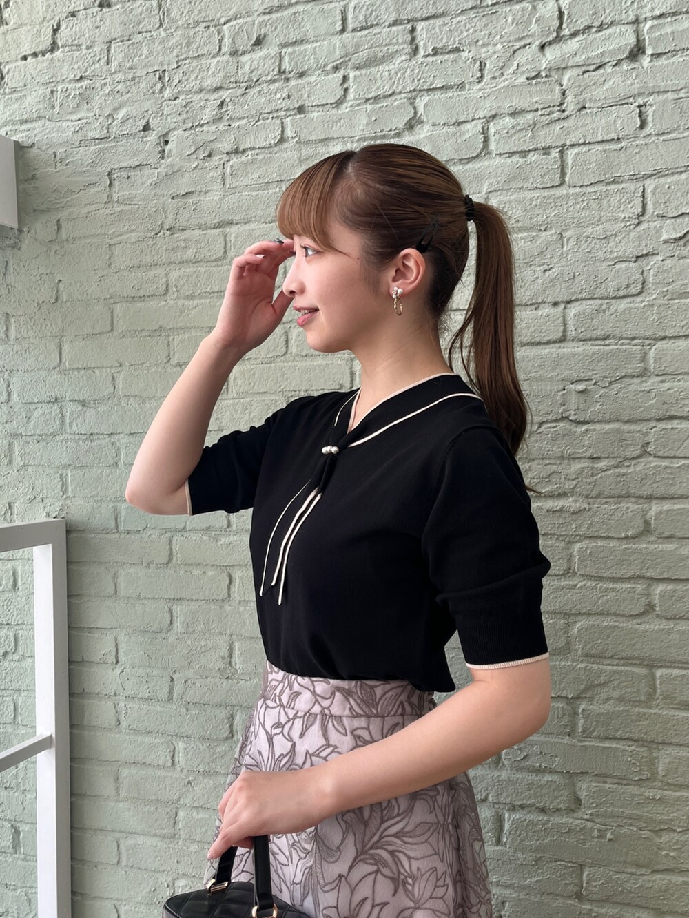 ブラック系のニット/セーター、グレー系のスカート、ブラック系のショルダーバッグを着用したレディースの夏コーディネートの4枚目の写真