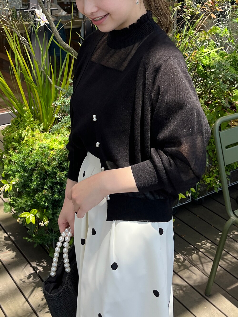 ブラック系のニット/セーター、ブラック系のカーディガン/ボレロ、ブラック系のハンドバッグを着用したレディースの夏コーディネートの4枚目の写真