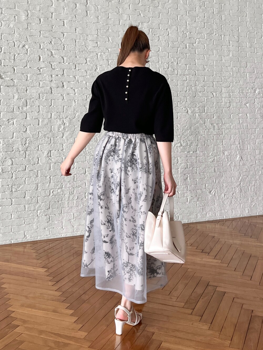 ブラック系のニット/セーター、グレー系のスカート、ホワイト系のショルダーバッグを着用したレディースの夏コーディネートの3枚目の写真