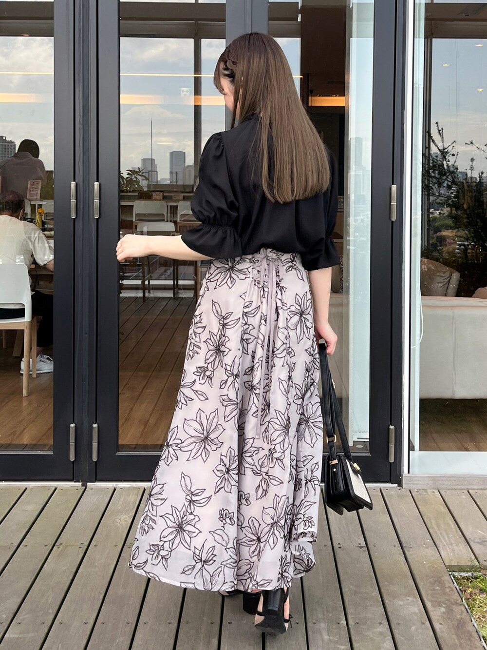 ブラウン系のスカート、ブラック系のシャツ/ブラウスを着用したレディースの夏コーディネートの2枚目の写真