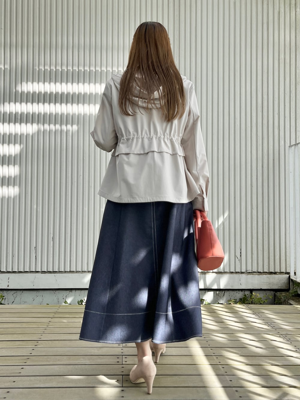 グレー系のブルゾン、ホワイト系のTシャツ/カットソー、ブルー系のスカートを着用したレディースの春コーディネートの3枚目の写真