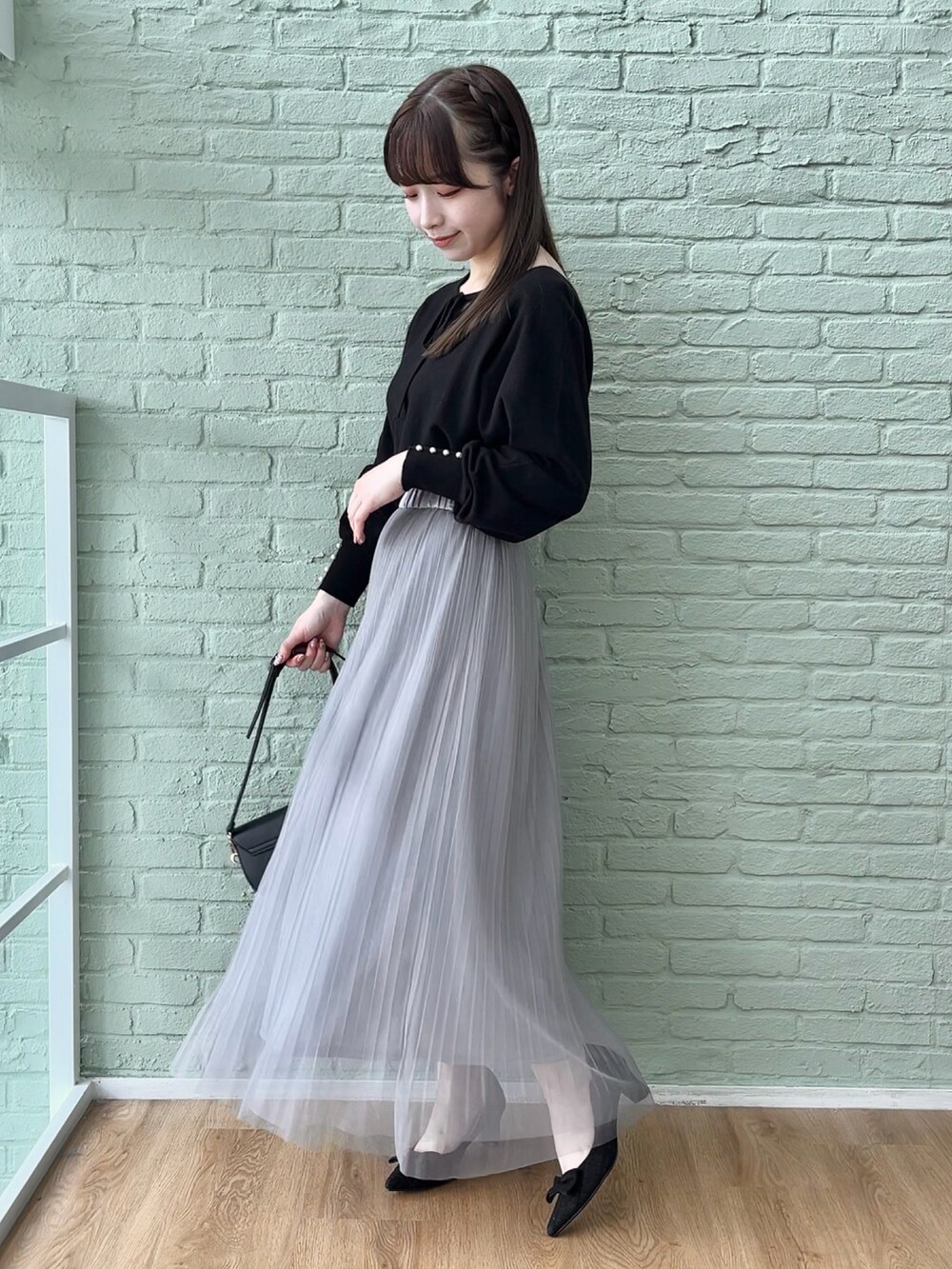 グレー系のスカート、ブラック系のニット/セーターを着用したレディースの秋コーディネートの2枚目の写真