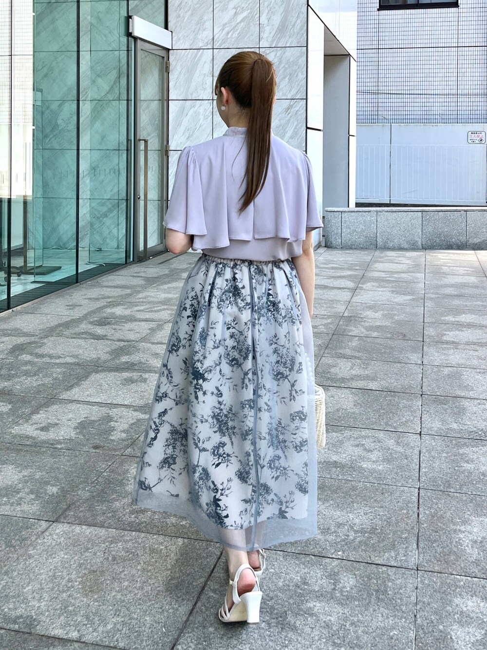 グレー系のシャツ/ブラウス、ベージュ系のハンドバッグ、ホワイト系のサンダルを着用したレディースの夏コーディネートの3枚目の写真