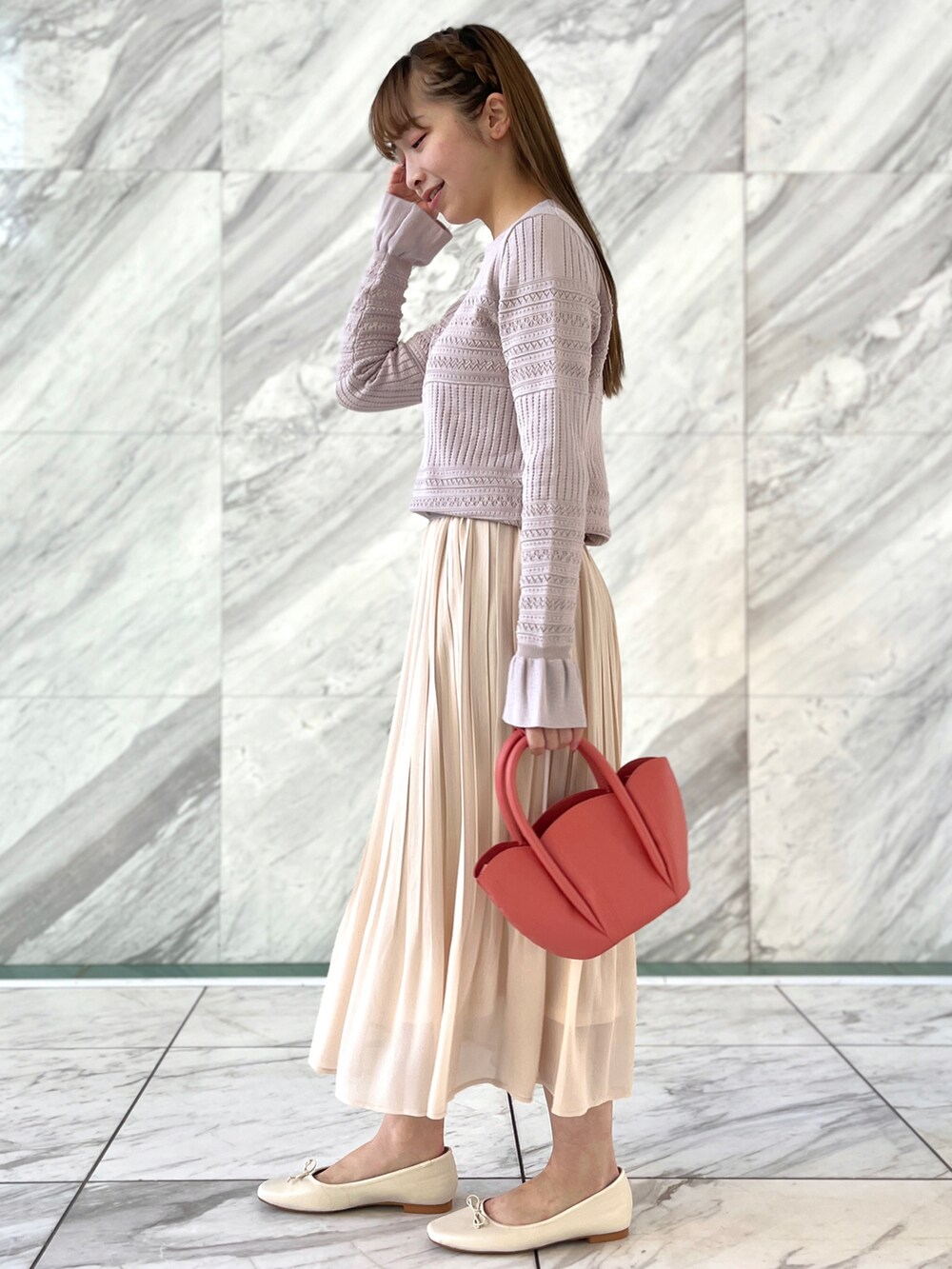 ピンク系のニット/セーター、ホワイト系のスカート、ホワイト系のパンプスを着用したレディースの冬コーディネートの2枚目の写真