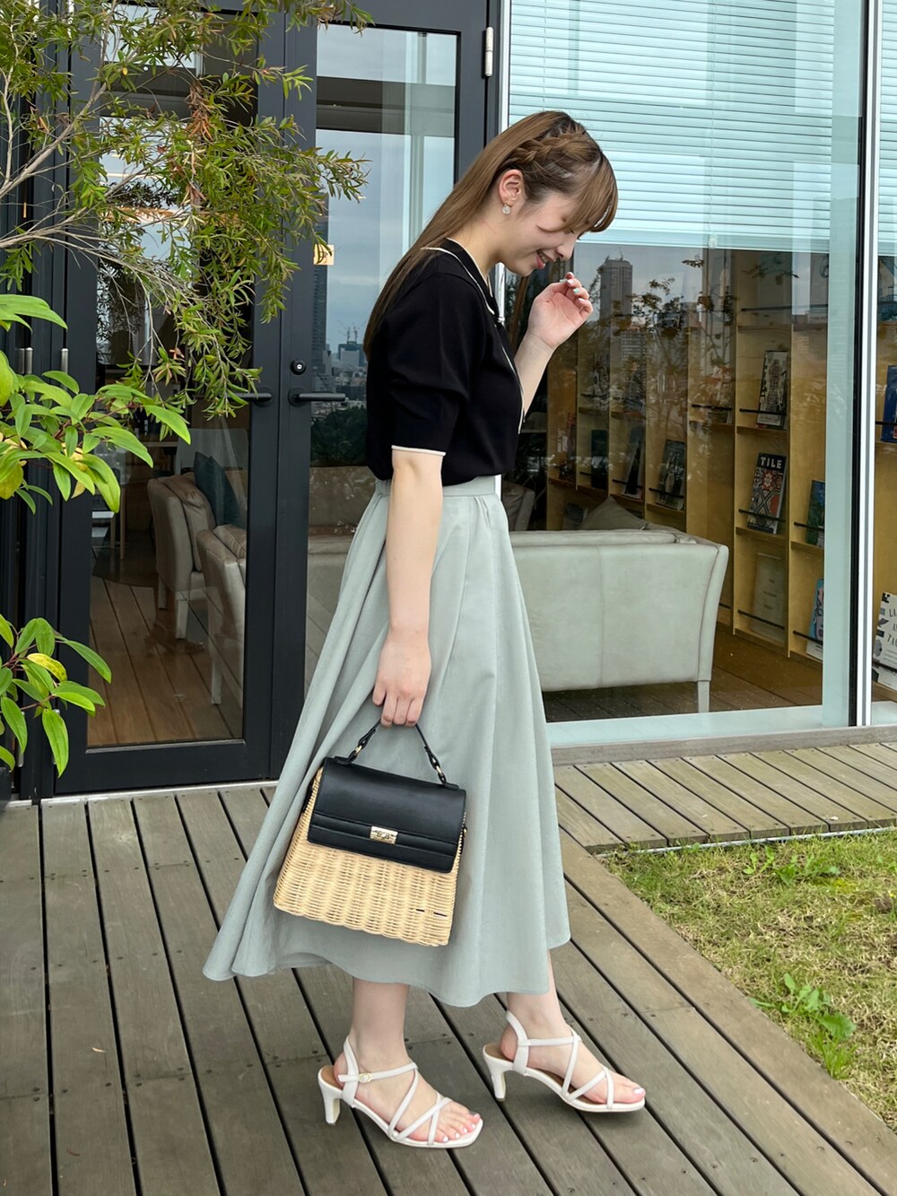 ブラック系のショルダーバッグ、ホワイト系のサンダル、グリーン系のスカートを着用したレディースの夏コーディネートの2枚目の写真