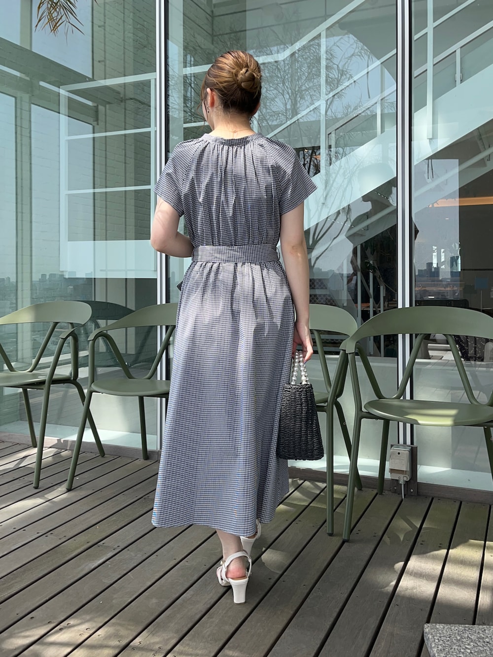 ブラック系のワンピース、ブラック系のハンドバッグ、ホワイト系のサンダルを着用したレディースの春コーディネートの3枚目の写真