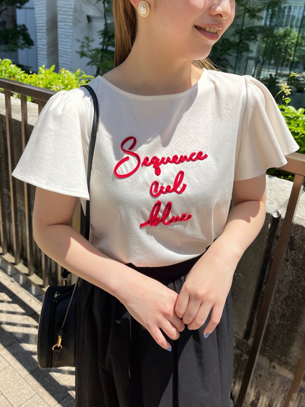 ホワイト系のTシャツ/カットソー、ブラック系のショルダーバッグ、ブラック系のスカートを着用したレディースの春コーディネートの4枚目の写真