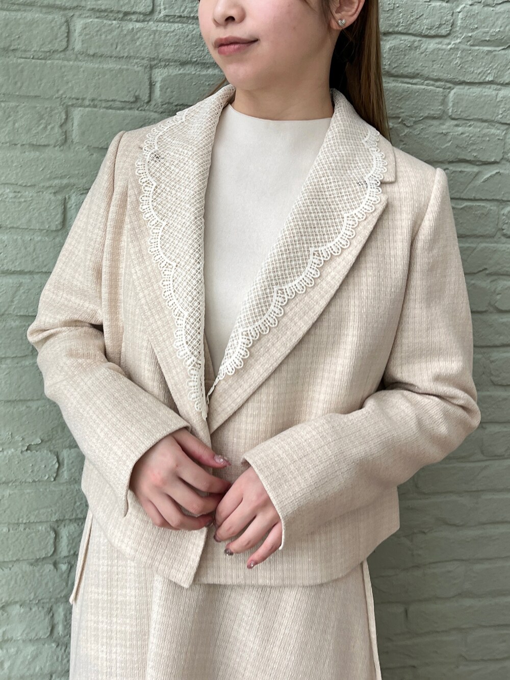 ベージュ系のテーラードジャケット、ベージュ系のワンピース、ホワイト系のニット/セーターを着用したレディースの春コーディネートの2枚目の写真