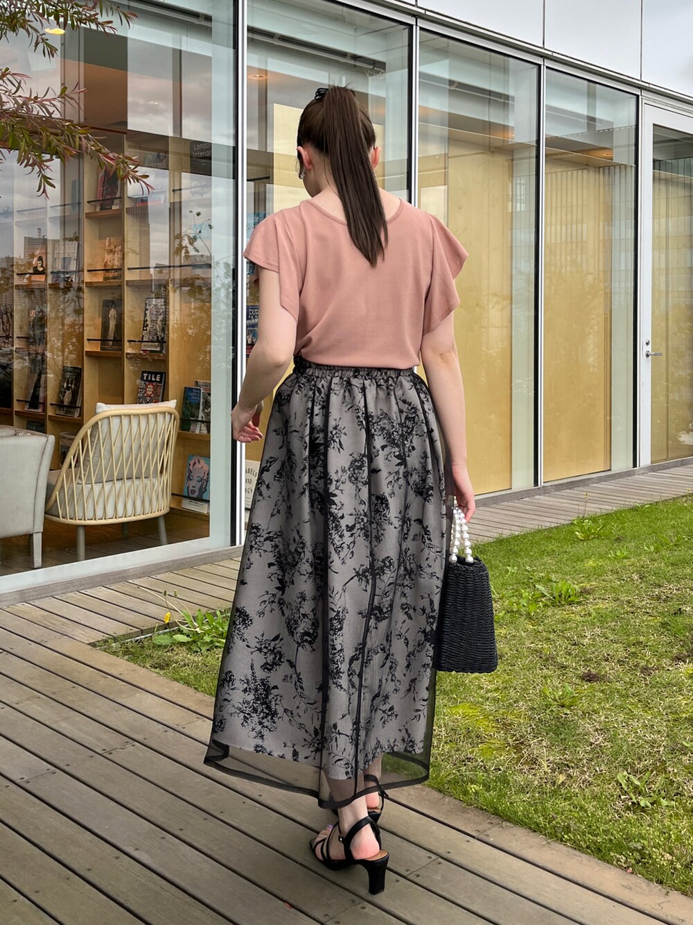 ブラック系のハンドバッグ、ブラック系のサンダル、ピンク系のニット/セーターを着用したレディースの夏コーディネートの3枚目の写真