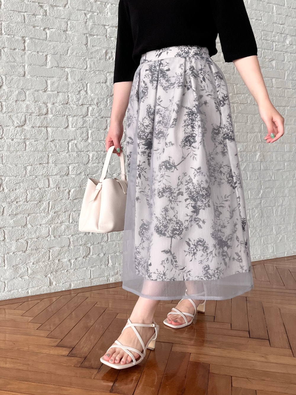 ブラック系のニット/セーター、グレー系のスカート、ホワイト系のショルダーバッグを着用したレディースの夏コーディネートの5枚目の写真