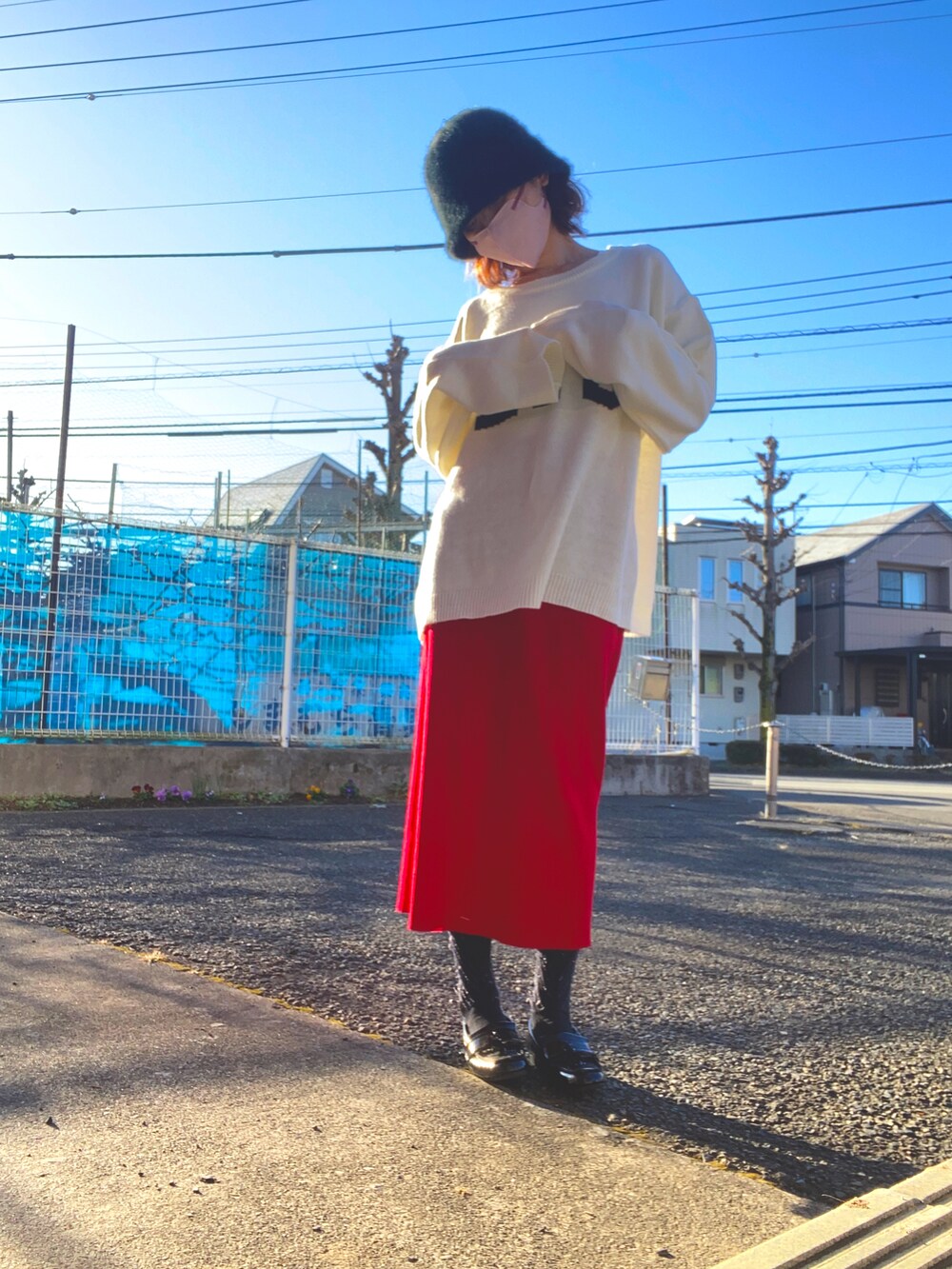 レッド系のスカート、ホワイト系のニット/セーター、ブラック系のローファーを着用したレディースの冬コーディネートの2枚目の写真