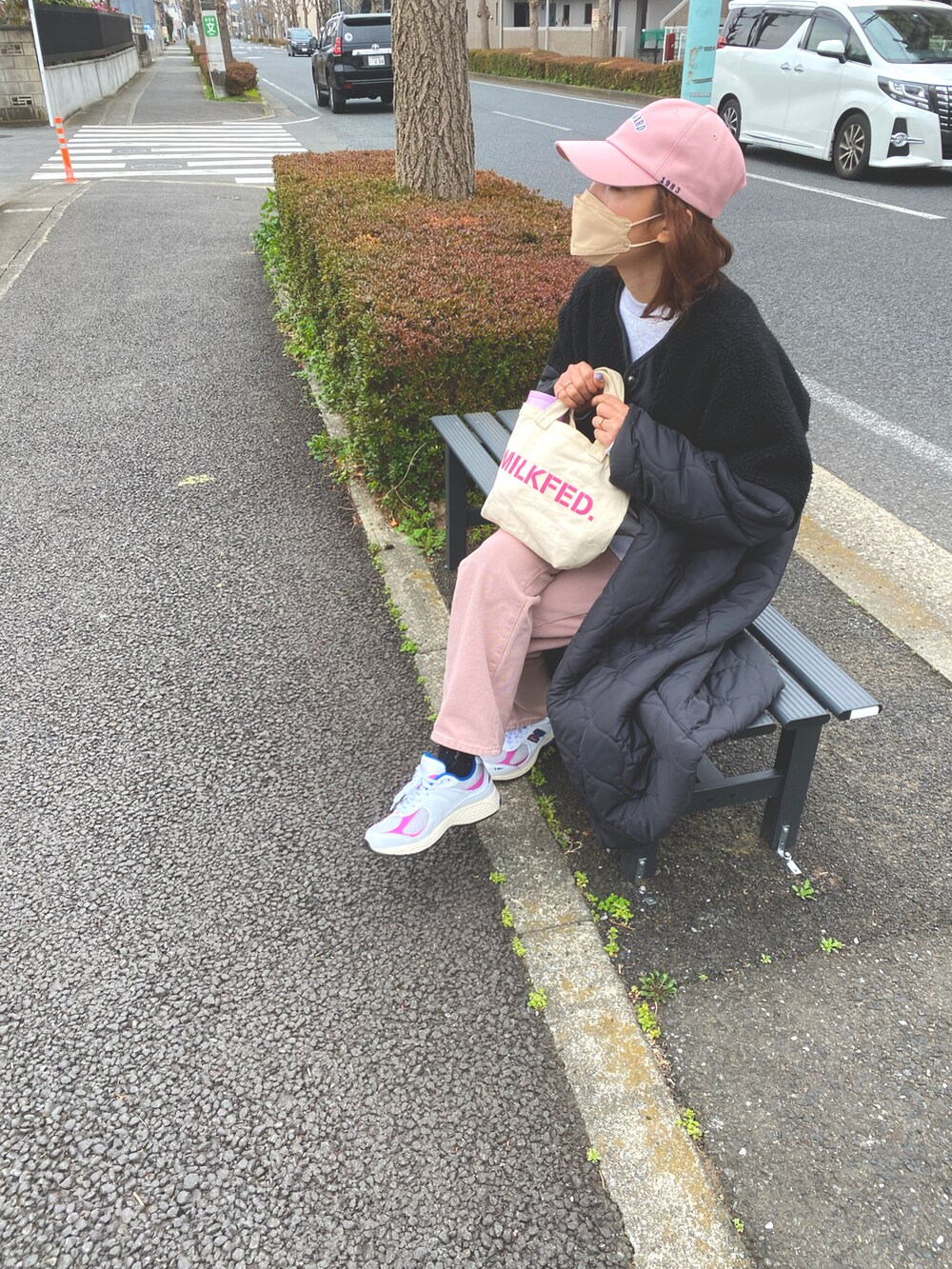 ホワイト系のトートバッグ、ブラック系のノーカラージャケット、ピンク系のデニムパンツを着用したレディースの春コーディネートの2枚目の写真