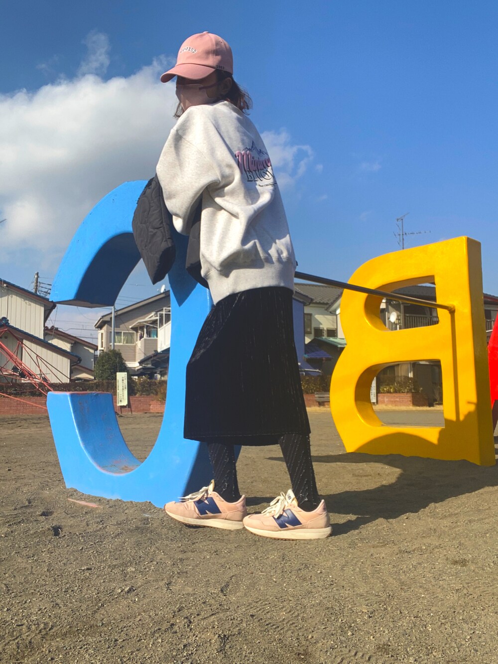 グレー系のスウェット、ブラック系のスカート、ピンク系のスニーカーを着用したレディースの冬コーディネートの2枚目の写真