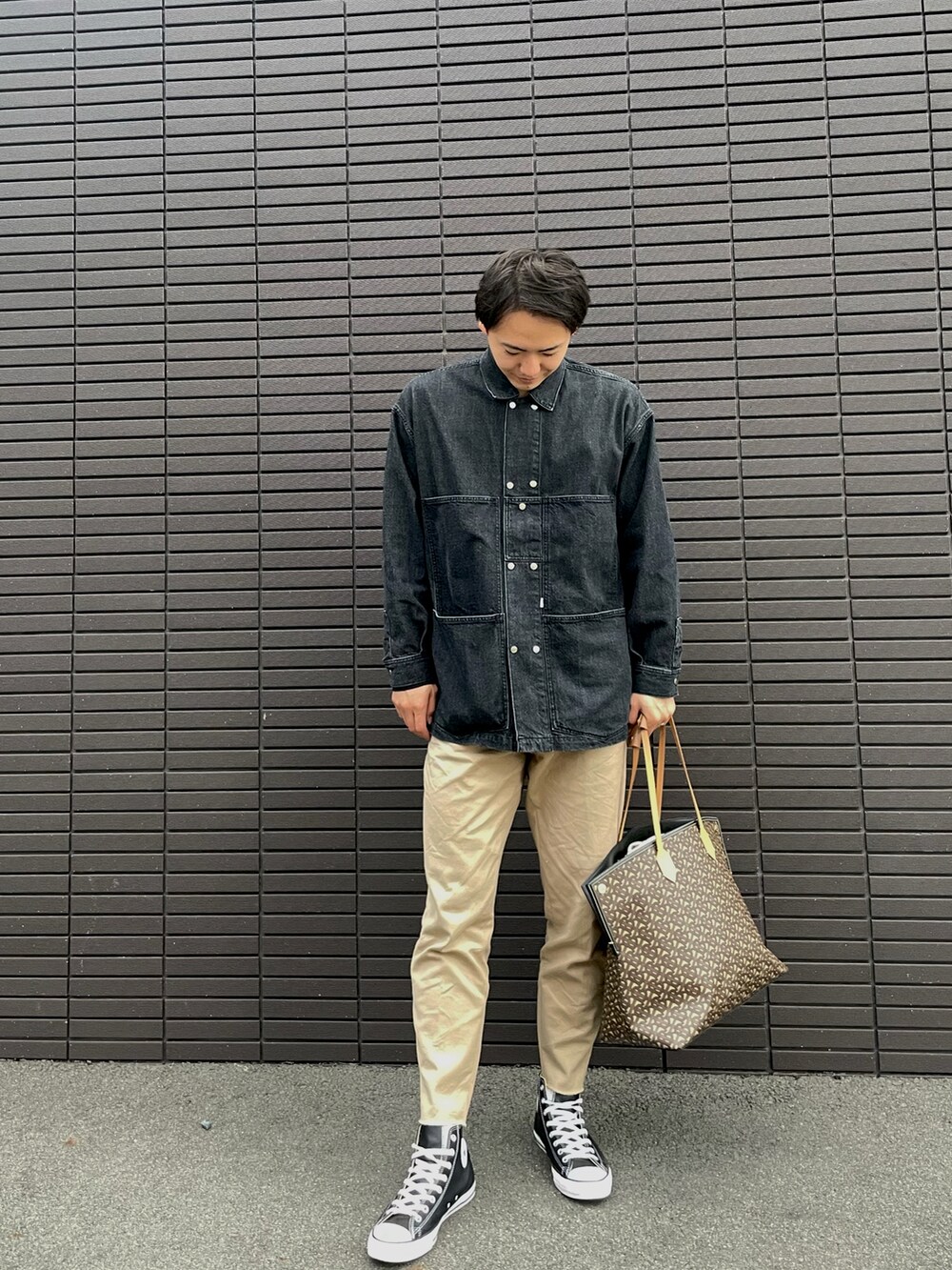 ブラック系のデニムジャケット、ブラウン系のトートバッグ、ベージュ系のチノパンツを着用したメンズの秋コーディネートの2枚目の写真