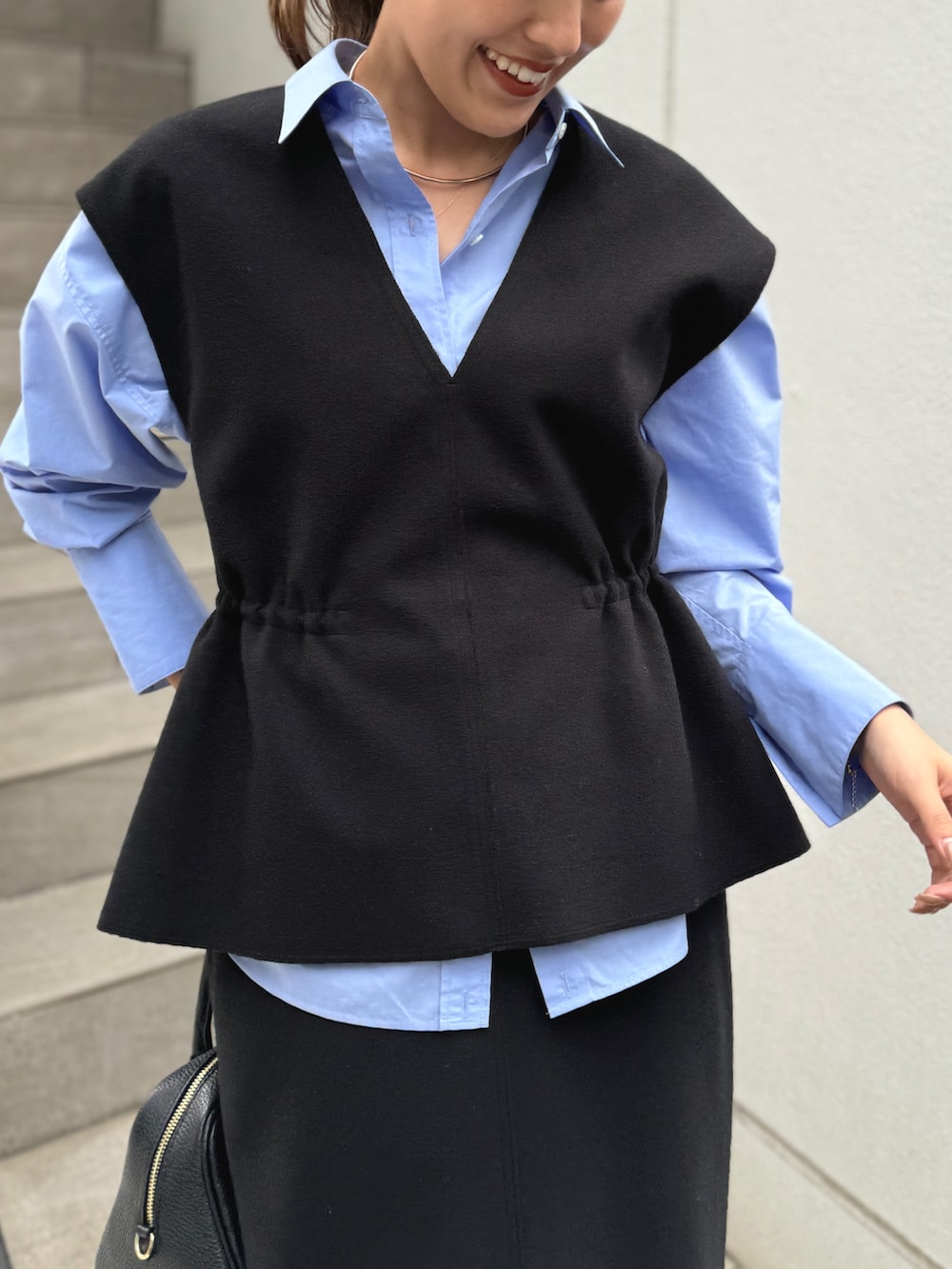 ブラック系のベスト、ブルー系のシャツ/ブラウス、ブラック系のショルダーバッグを着用したレディースの秋コーディネートの3枚目の写真