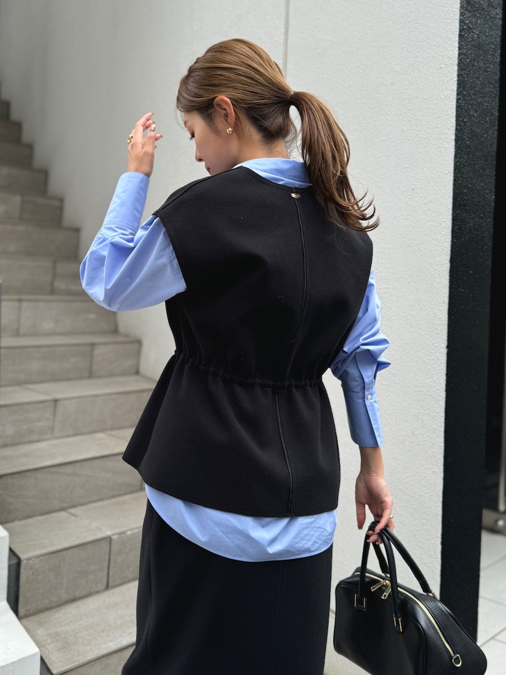 ブラック系のベスト、ブルー系のシャツ/ブラウス、ブラック系のショルダーバッグを着用したレディースの秋コーディネートの5枚目の写真