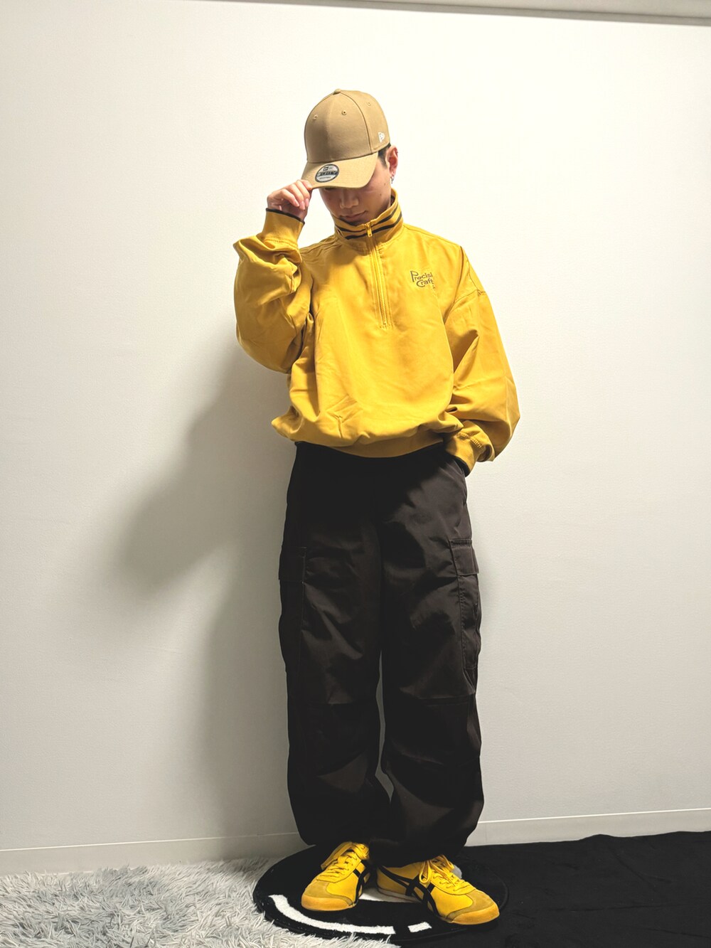 イエロー系のスウェット、ブラウン系のカーゴパンツ、イエロー系のスニーカーを着用したメンズの冬コーディネートの2枚目の写真