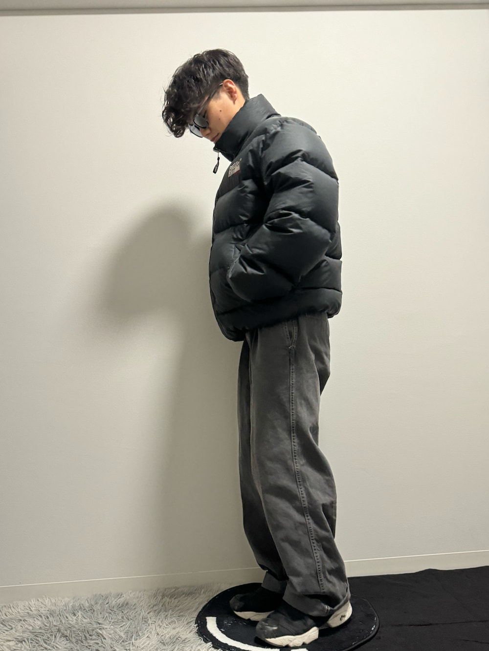 ブラック系のデニムパンツ、ブラック系のスニーカー、ブラック系のダウンジャケット/コートを着用したメンズの冬コーディネートの3枚目の写真