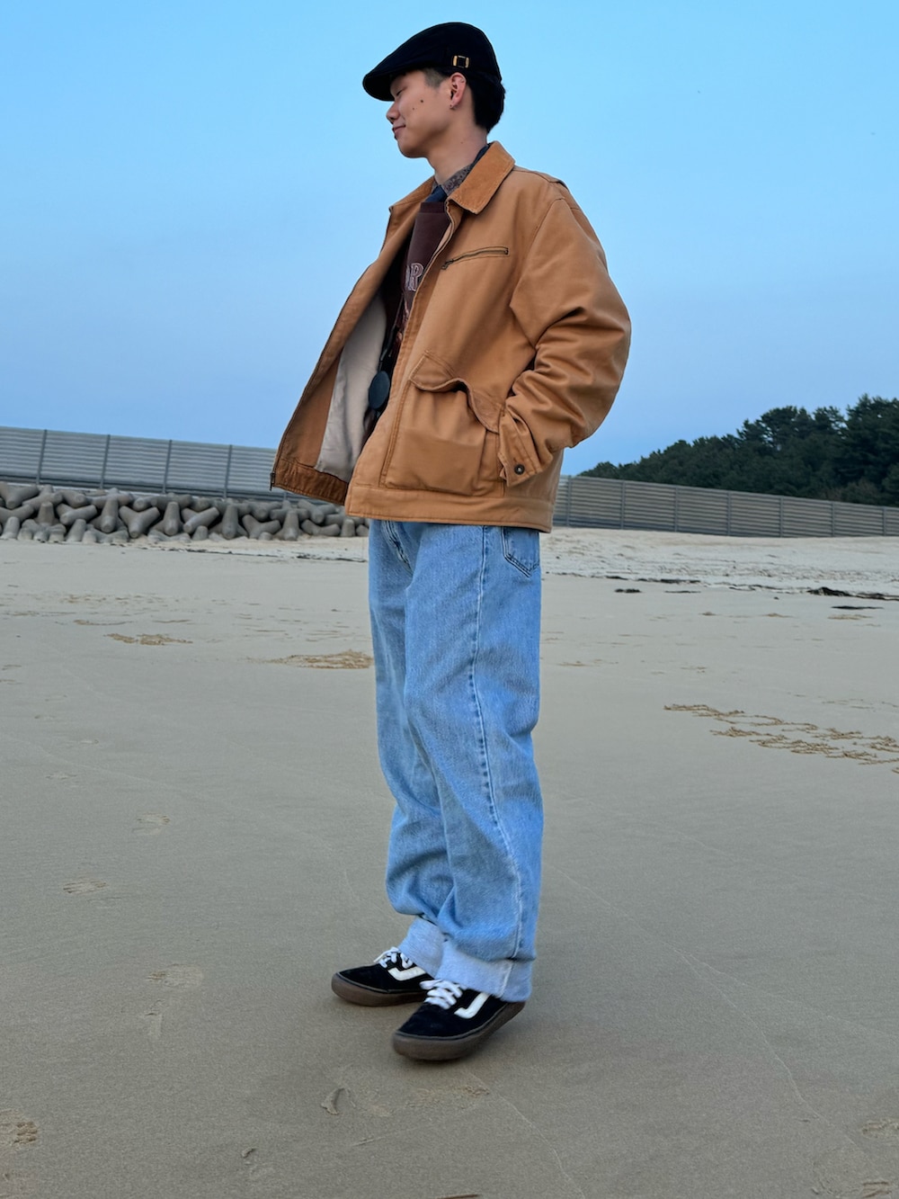 ブラウン系のスウェット、ベージュ系のブルゾン、ブルー系のデニムパンツを着用したメンズの春コーディネートの2枚目の写真