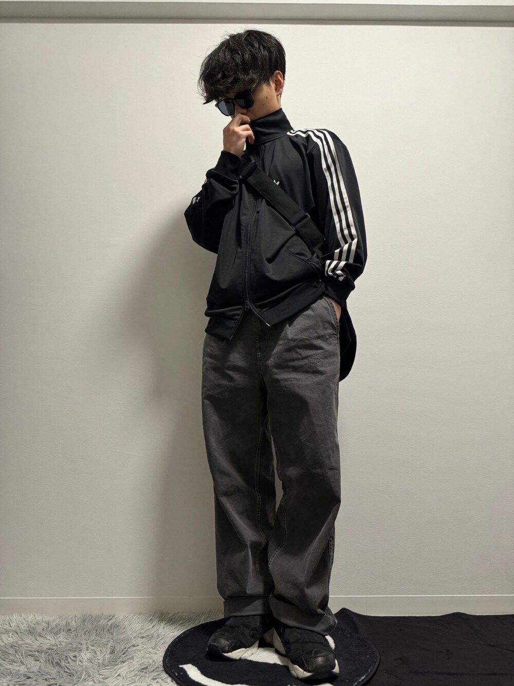 ブラック系のデニムパンツ、ブラック系のスニーカー、ブラック系のナイロンジャケットを着用したメンズの冬コーディネートの4枚目の写真
