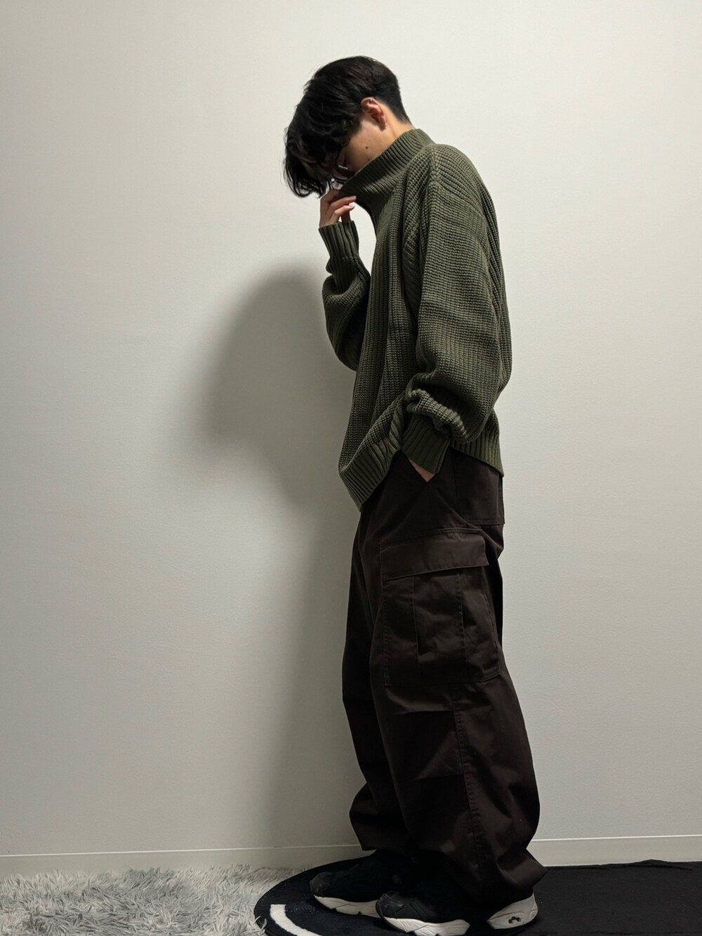 グリーン系のニット/セーター、ブラウン系のカーゴパンツ、ブラック系のスニーカーを着用したメンズの春コーディネートの3枚目の写真