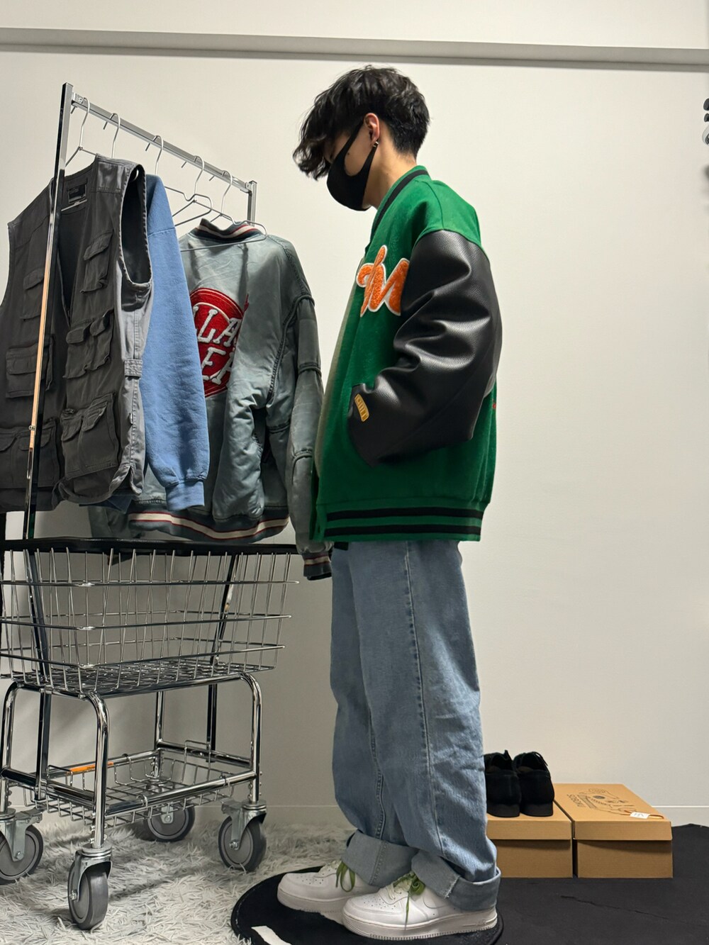 ブルー系のデニムパンツ、ホワイト系のスニーカー、グリーン系のタンクトップを着用したメンズの冬コーディネートの3枚目の写真