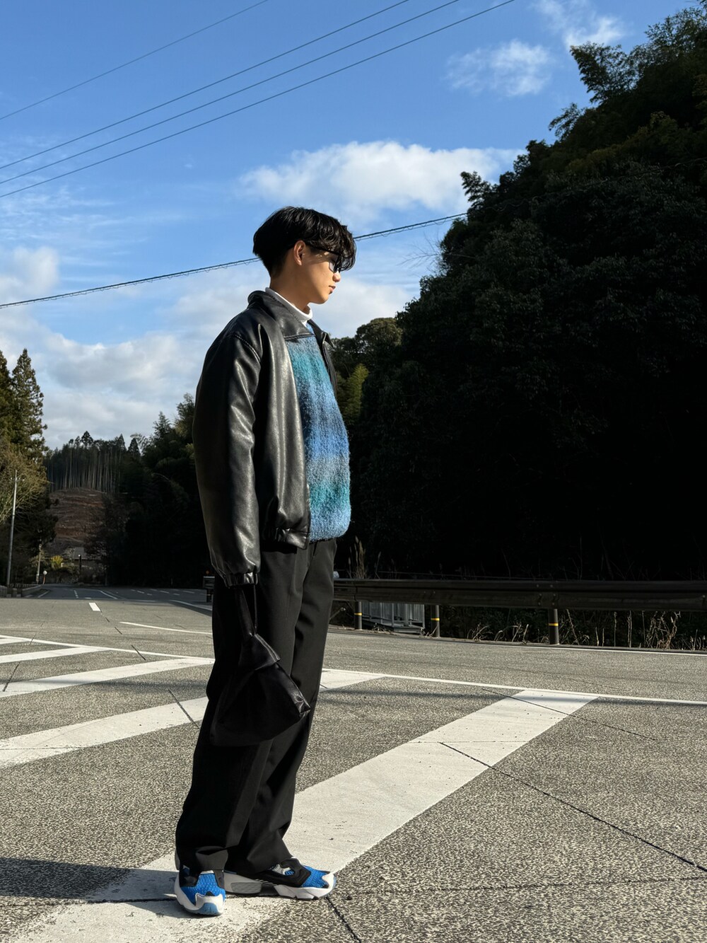ブルー系のスニーカー、ブラック系のハンドバッグ、ブラック系のスラックスを着用したメンズの春コーディネートの2枚目の写真
