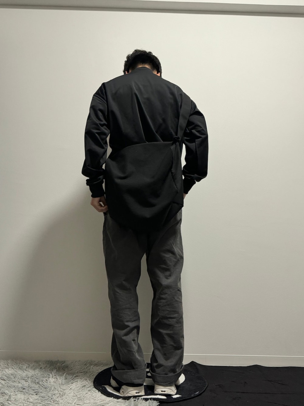 ブラック系のデニムパンツ、ブラック系のスニーカー、ブラック系のナイロンジャケットを着用したメンズの冬コーディネートの5枚目の写真