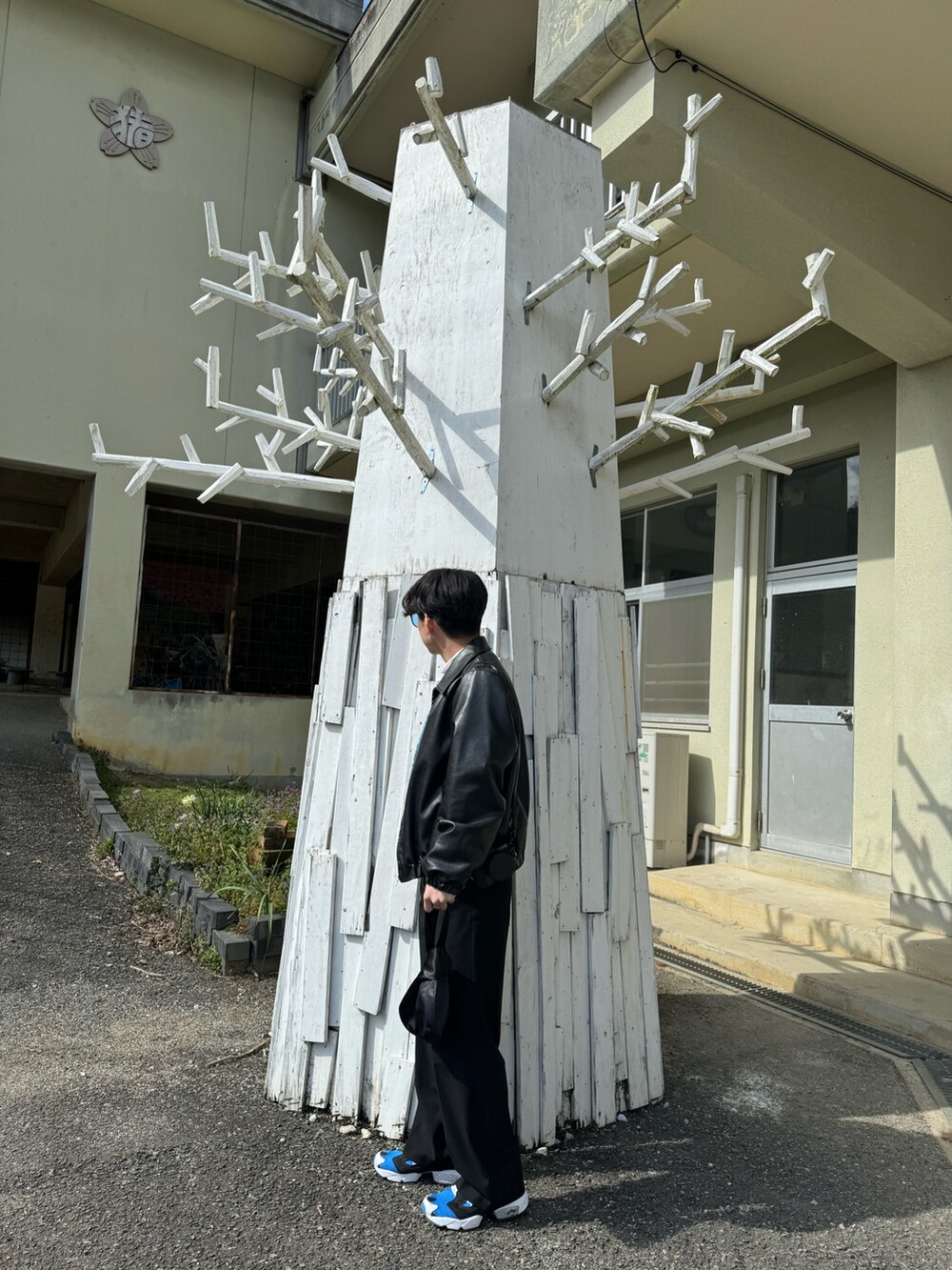ブルー系のスニーカー、ブラック系のハンドバッグ、ブラック系のスラックスを着用したメンズの春コーディネートの4枚目の写真
