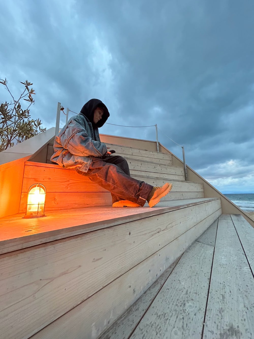 ブルー系のスカジャン、ブラック系のパーカー、ブラウン系のサロペット/オーバーオールを着用したメンズの冬コーディネートの2枚目の写真