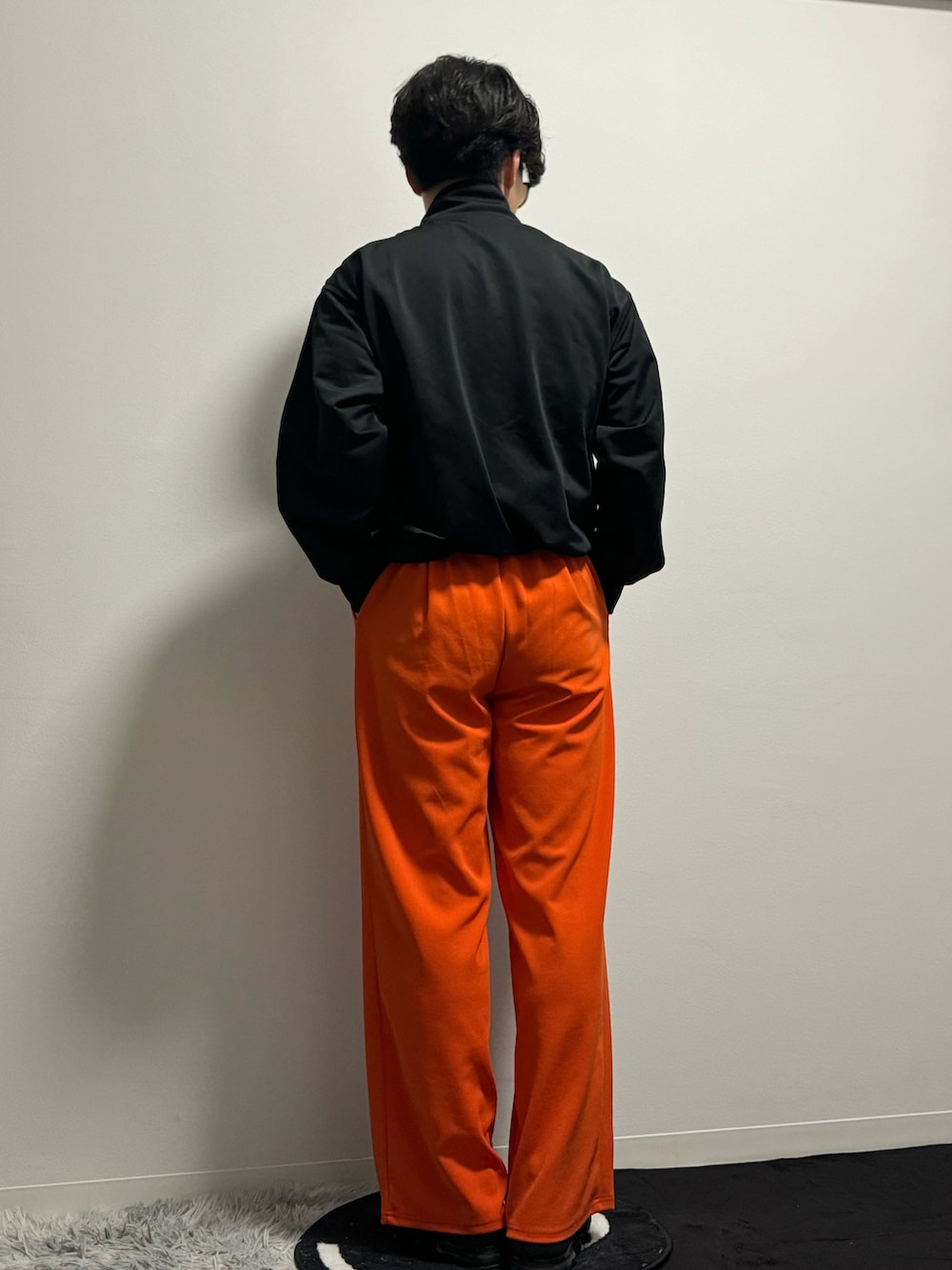 オレンジ系のスラックス、ブラック系のブルゾン、ブラック系のスニーカーを着用したメンズの春コーディネートの5枚目の写真