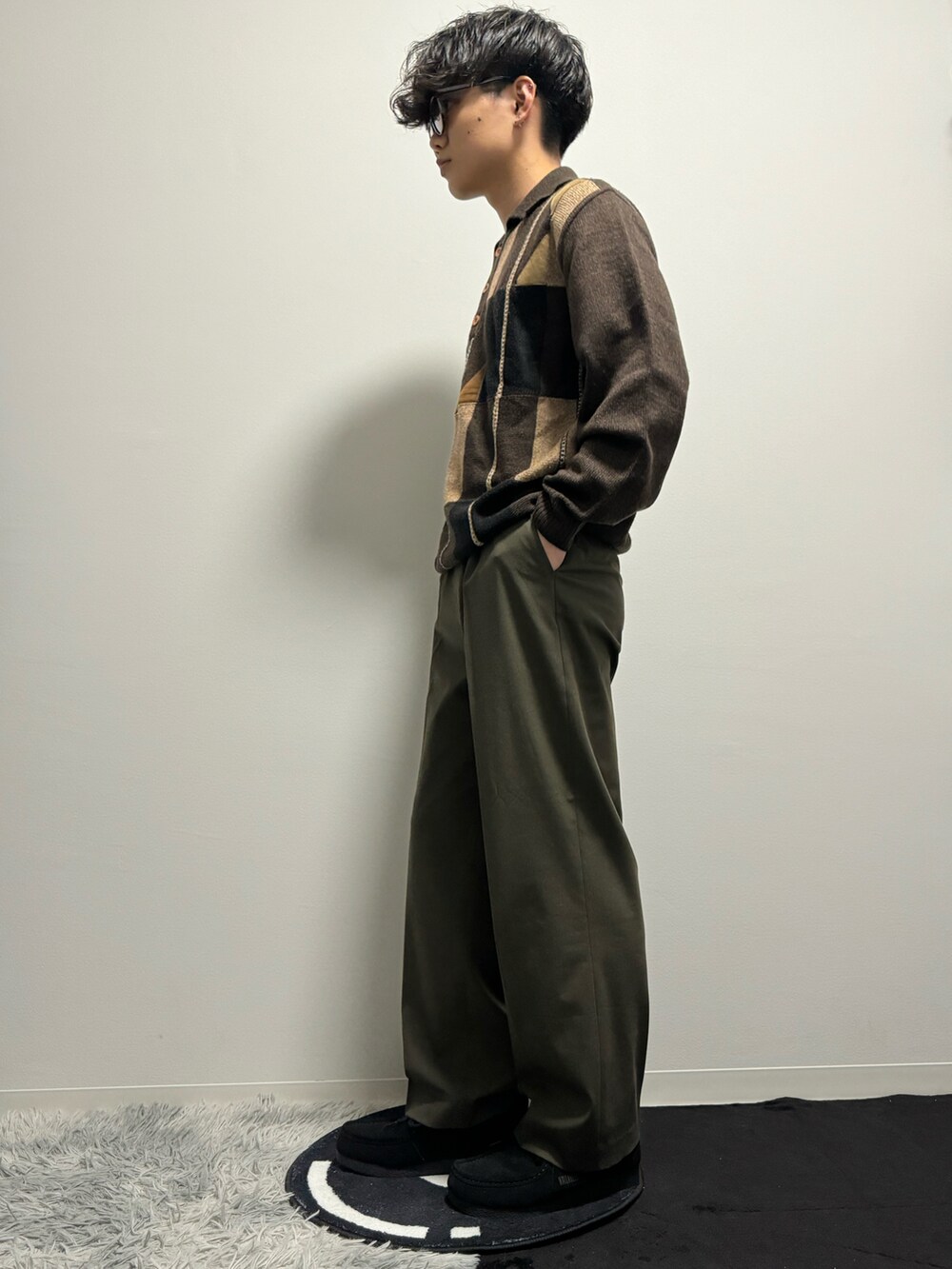 グリーン系のスラックス、ブラック系のモカシン/デッキシューズ、ブラウン系のポロシャツを着用したメンズの春コーディネートの5枚目の写真