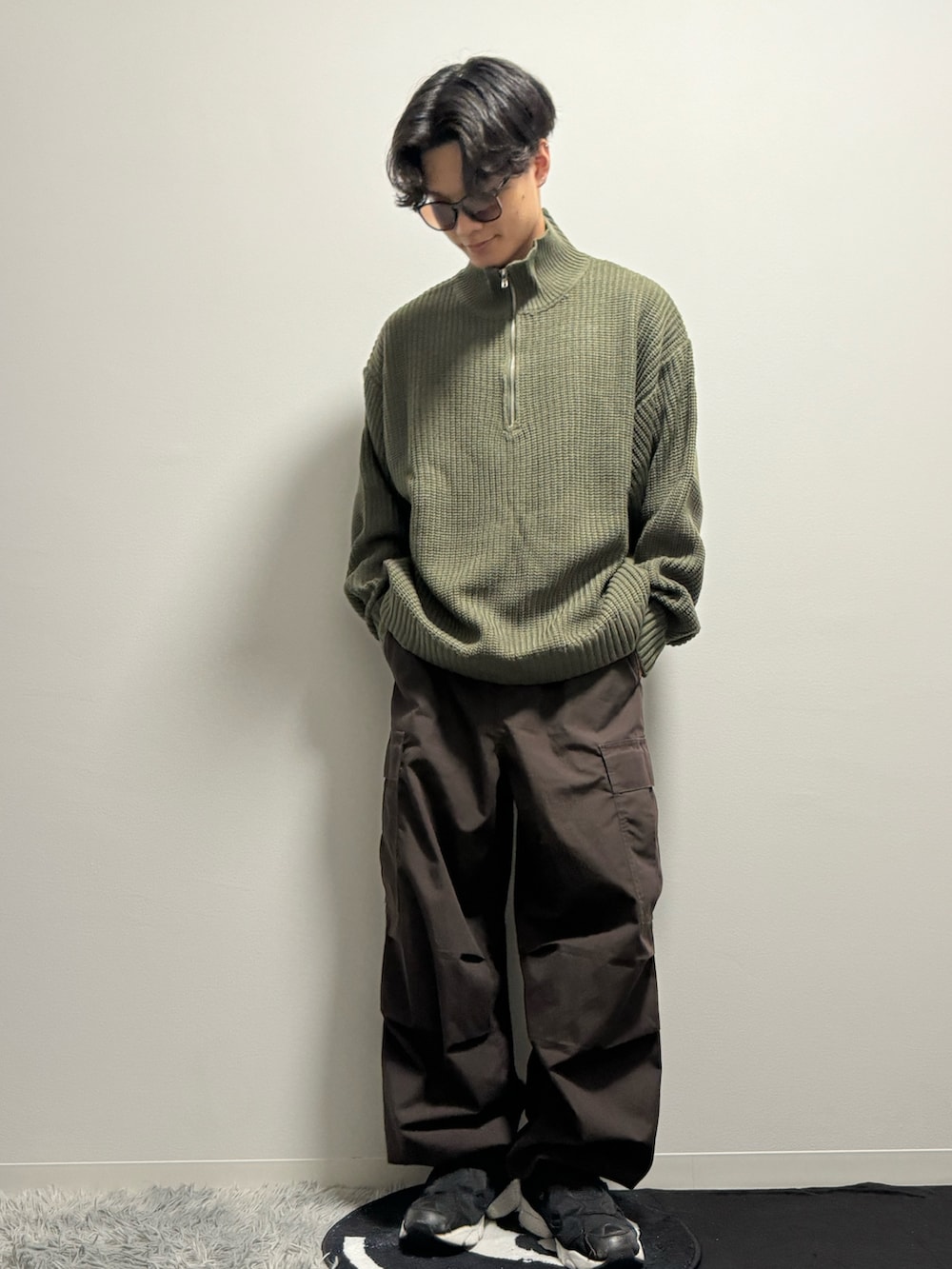 グリーン系のニット/セーター、ブラウン系のカーゴパンツ、ブラック系のスニーカーを着用したメンズの春コーディネートの2枚目の写真