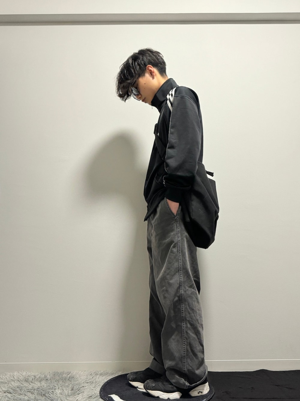 ブラック系のデニムパンツ、ブラック系のスニーカー、ブラック系のナイロンジャケットを着用したメンズの冬コーディネートの3枚目の写真