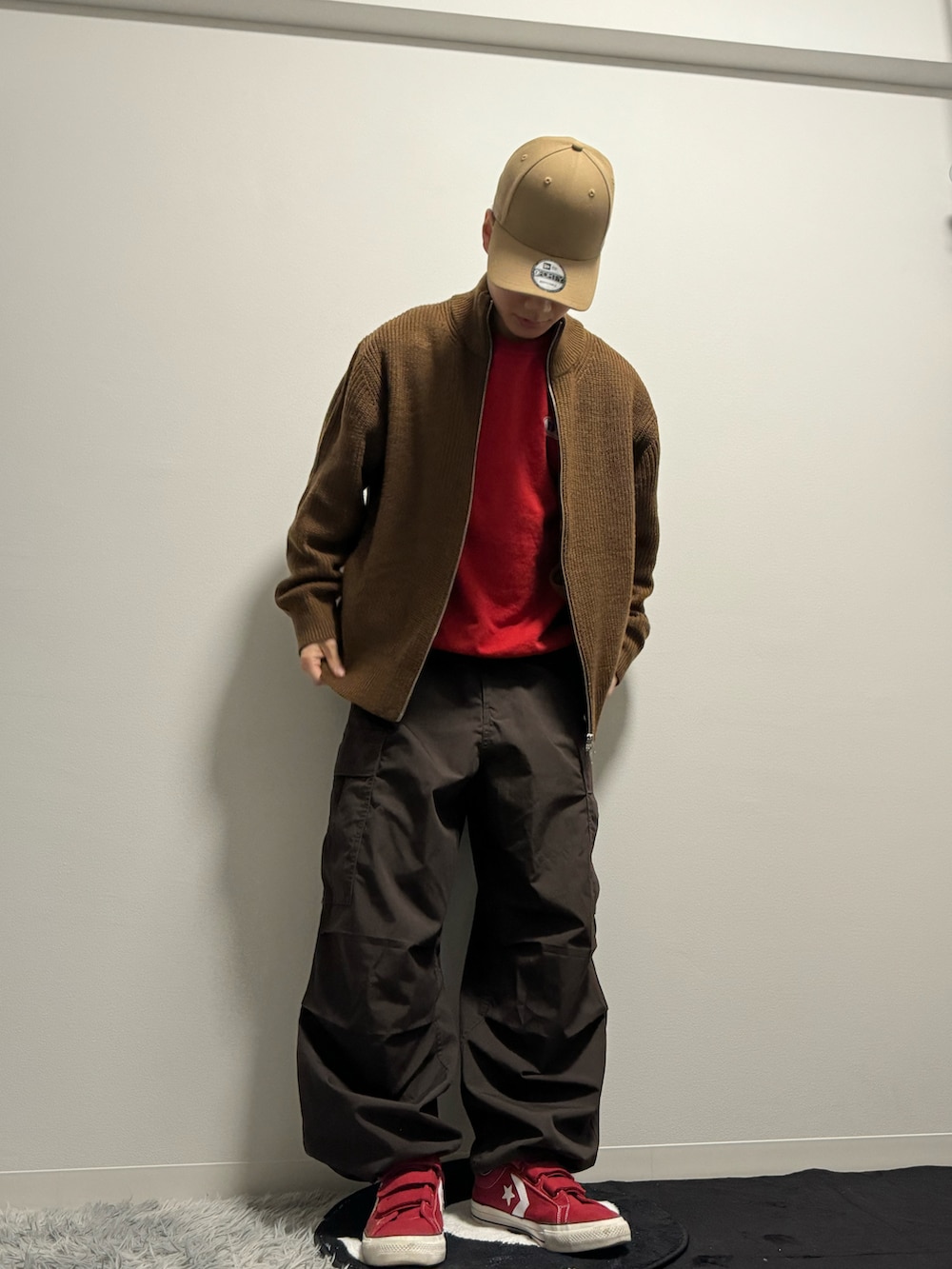 ブラウン系のニット/セーター、ブラウン系のカーゴパンツ、レッド系のスウェットを着用したメンズの冬コーディネートの3枚目の写真