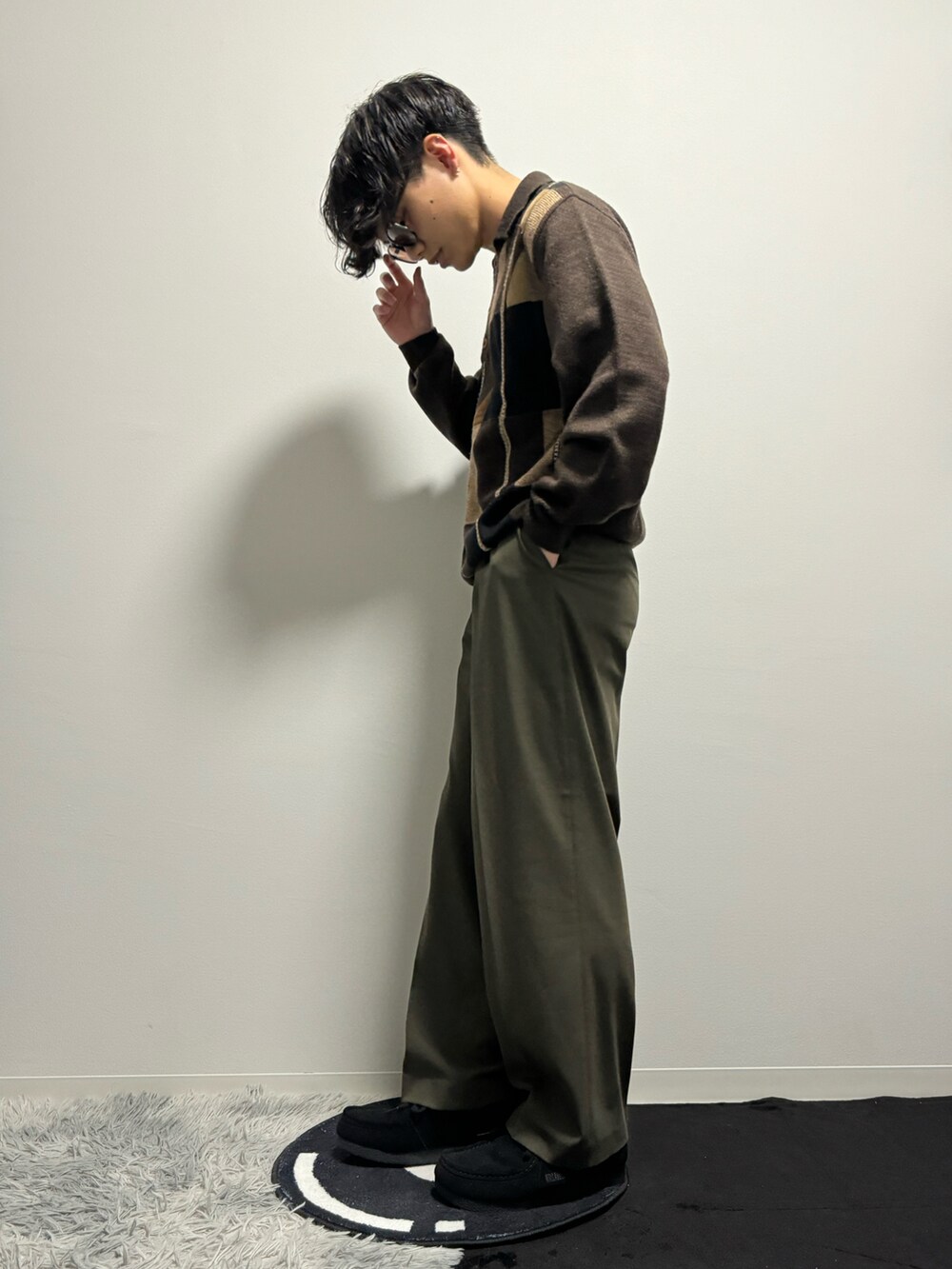 グリーン系のスラックス、ブラック系のモカシン/デッキシューズ、ブラウン系のポロシャツを着用したメンズの春コーディネートの2枚目の写真