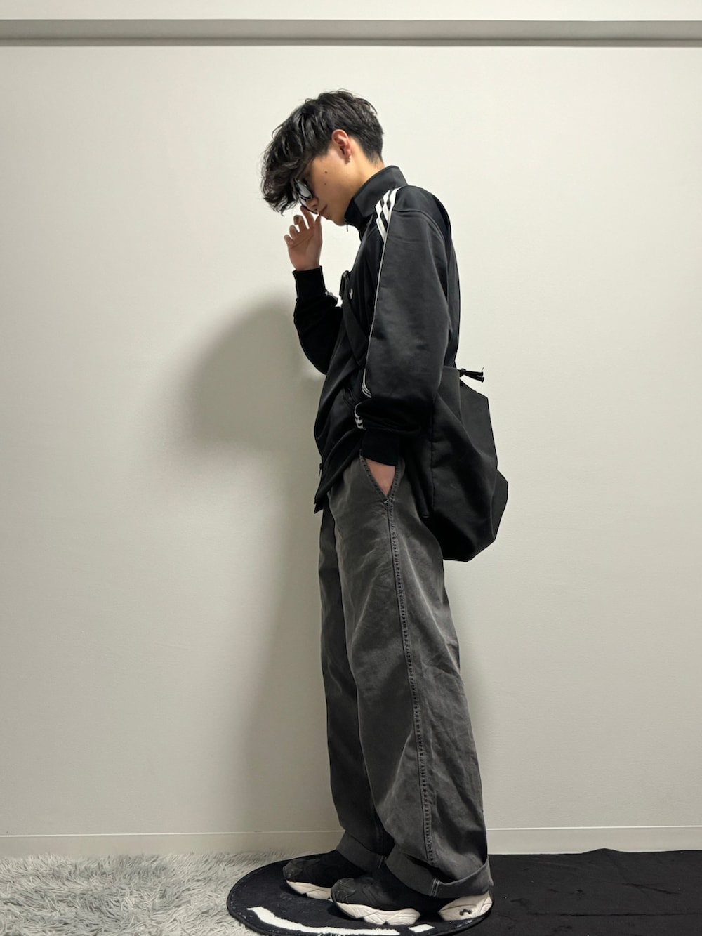 ブラック系のデニムパンツ、ブラック系のスニーカー、ブラック系のナイロンジャケットを着用したメンズの冬コーディネートの2枚目の写真
