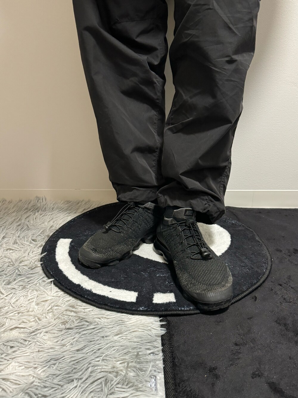 イエロー系のナイロンジャケット、ブラック系のカーゴパンツ、ブラック系のスニーカーを着用したメンズの春コーディネートの5枚目の写真