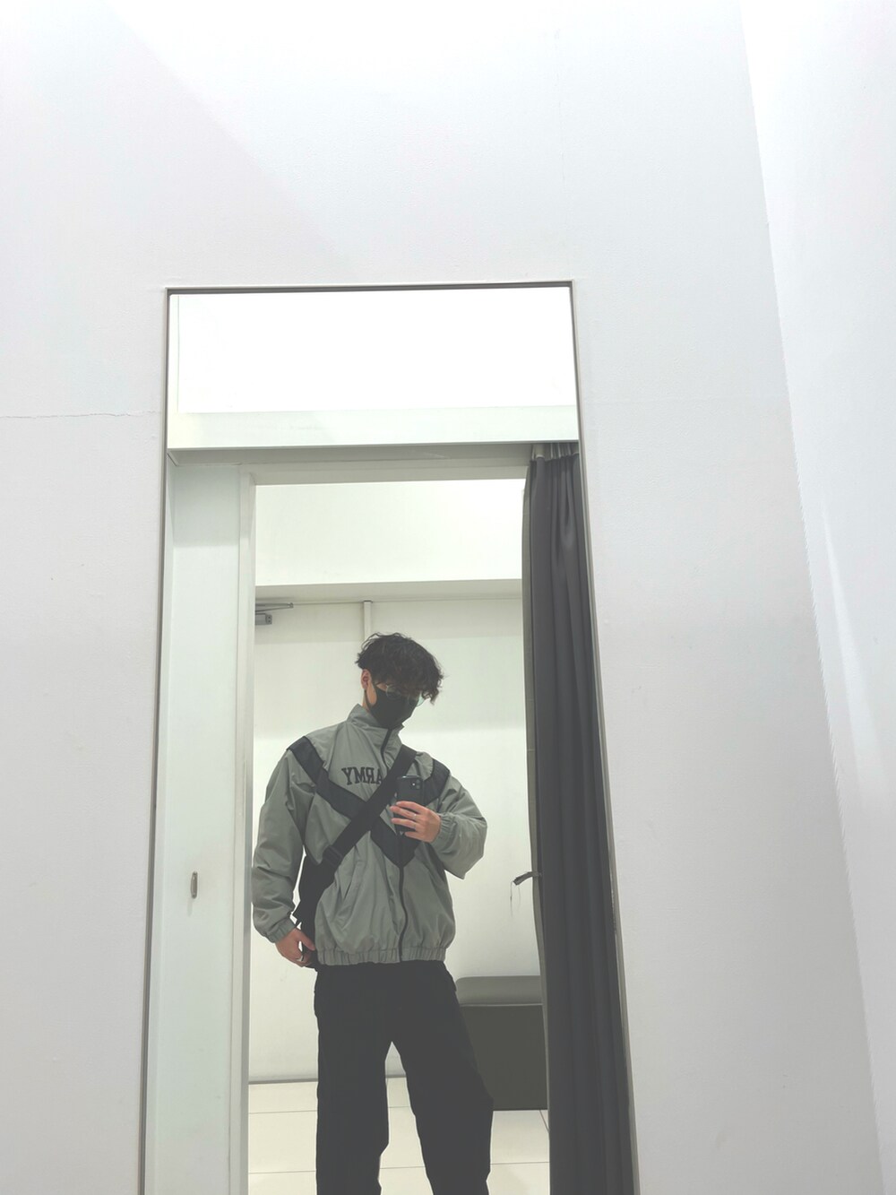 グリーン系のナイロンジャケット、ブラック系のカーゴパンツ、ホワイト系のスニーカーを着用したメンズの冬コーディネートの2枚目の写真