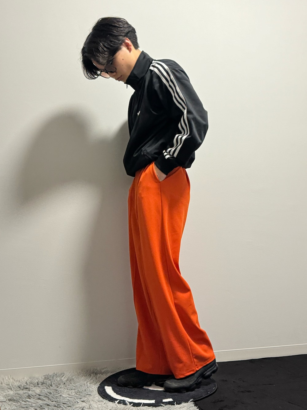 オレンジ系のスラックス、ブラック系のブルゾン、ブラック系のスニーカーを着用したメンズの春コーディネートの4枚目の写真