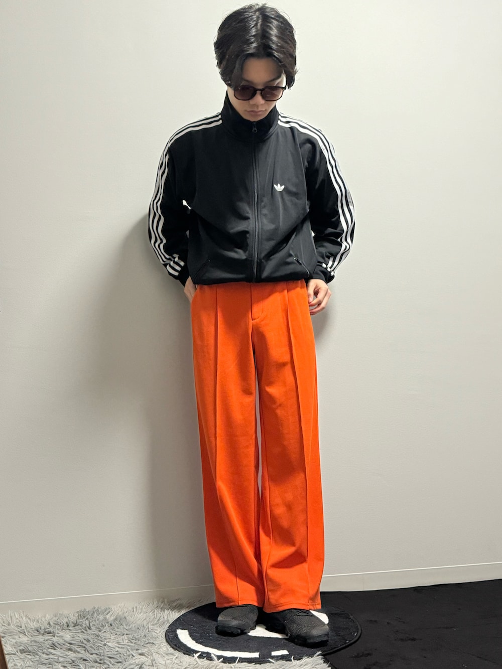オレンジ系のスラックス、ブラック系のブルゾン、ブラック系のスニーカーを着用したメンズの春コーディネートの2枚目の写真
