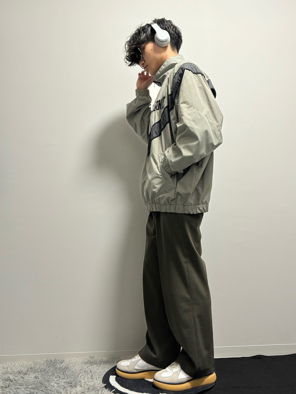 グリーン系のスラックス、グリーン系のスニーカー、グリーン系のミリタリージャケットを着用したメンズの春コーディネートの2枚目の写真