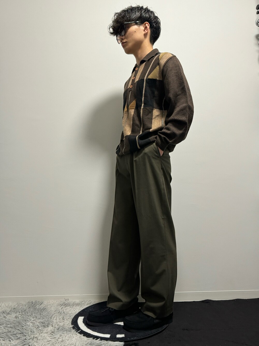 グリーン系のスラックス、ブラック系のモカシン/デッキシューズ、ブラウン系のポロシャツを着用したメンズの春コーディネートの3枚目の写真