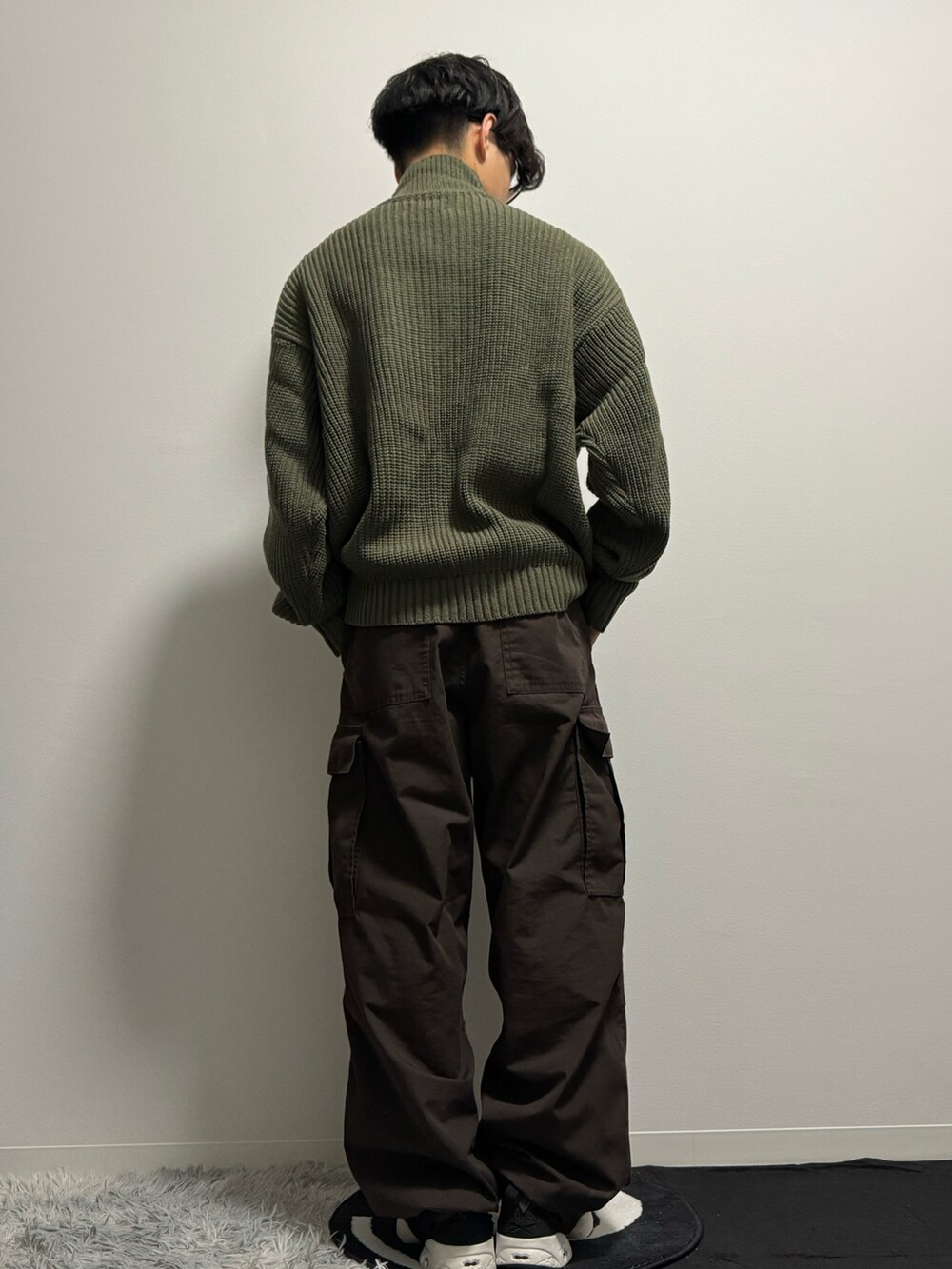 グリーン系のニット/セーター、ブラウン系のカーゴパンツ、ブラック系のスニーカーを着用したメンズの春コーディネートの4枚目の写真