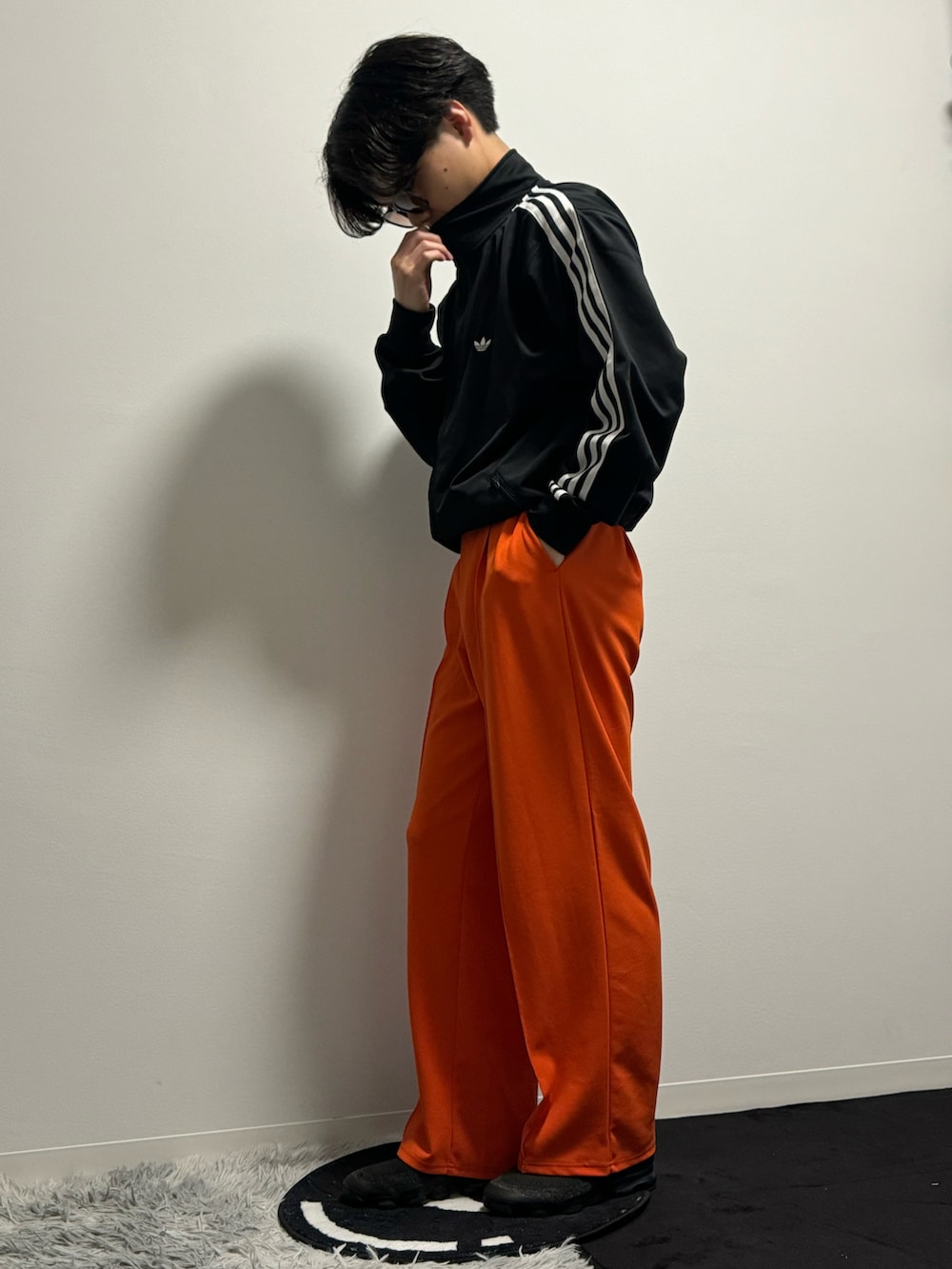 オレンジ系のスラックス、ブラック系のブルゾン、ブラック系のスニーカーを着用したメンズの春コーディネートの3枚目の写真
