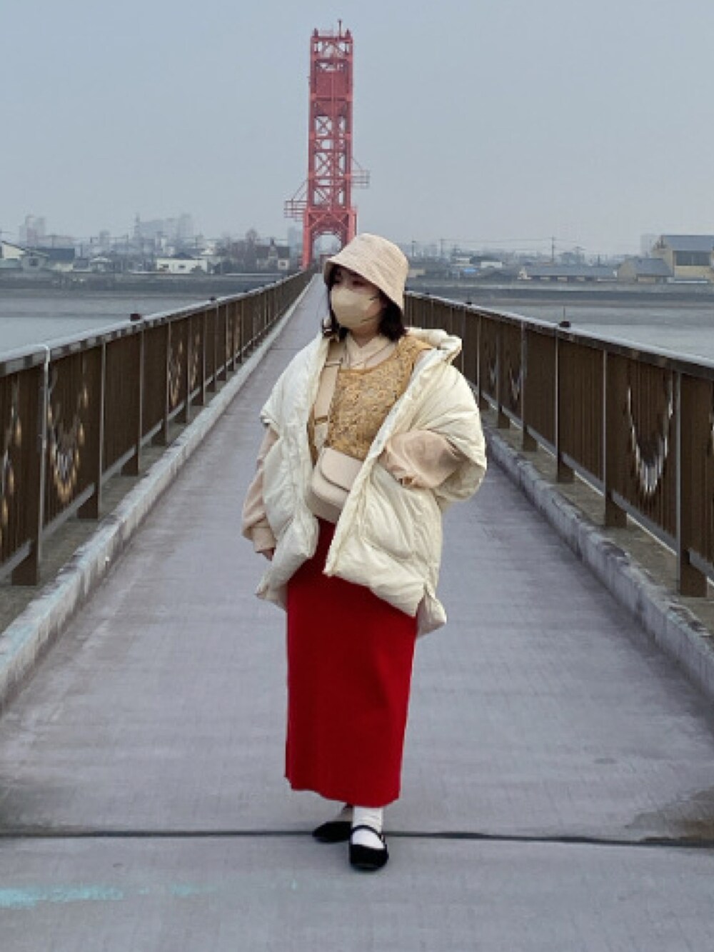 イエロー系のトップス、ホワイト系のショルダーバッグ、レッド系のスカートを着用したレディースの冬コーディネートの2枚目の写真