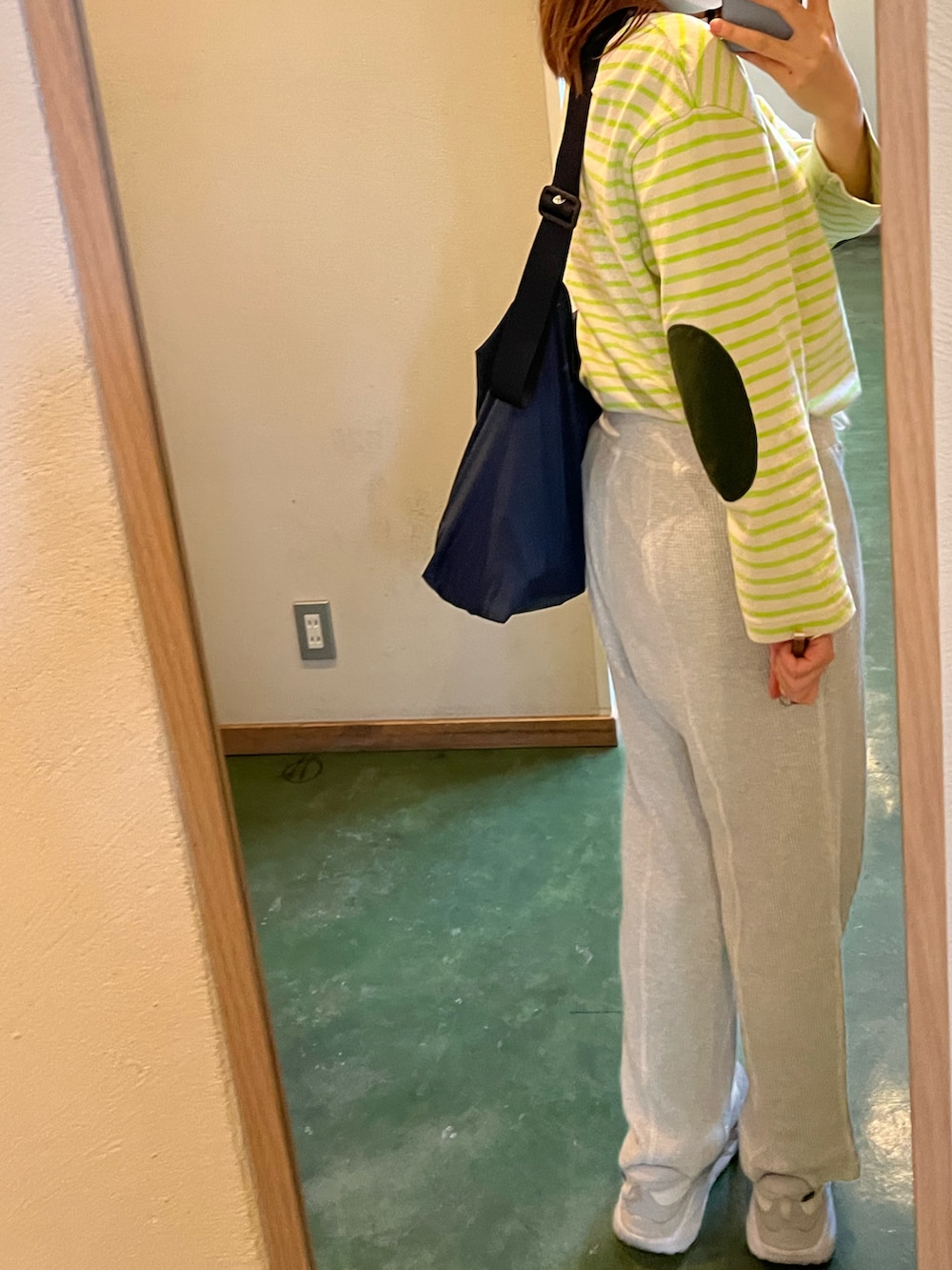 グレー系のパンツ、グリーン系のトップス、グレー系のスニーカーを着用したレディースの冬コーディネートの2枚目の写真